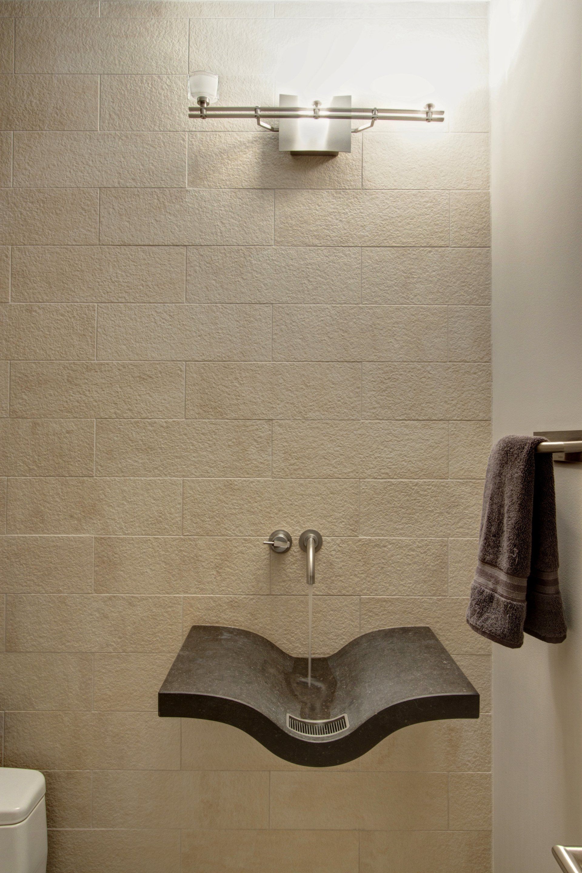 A bathroom with a curved sink and a toilet.
