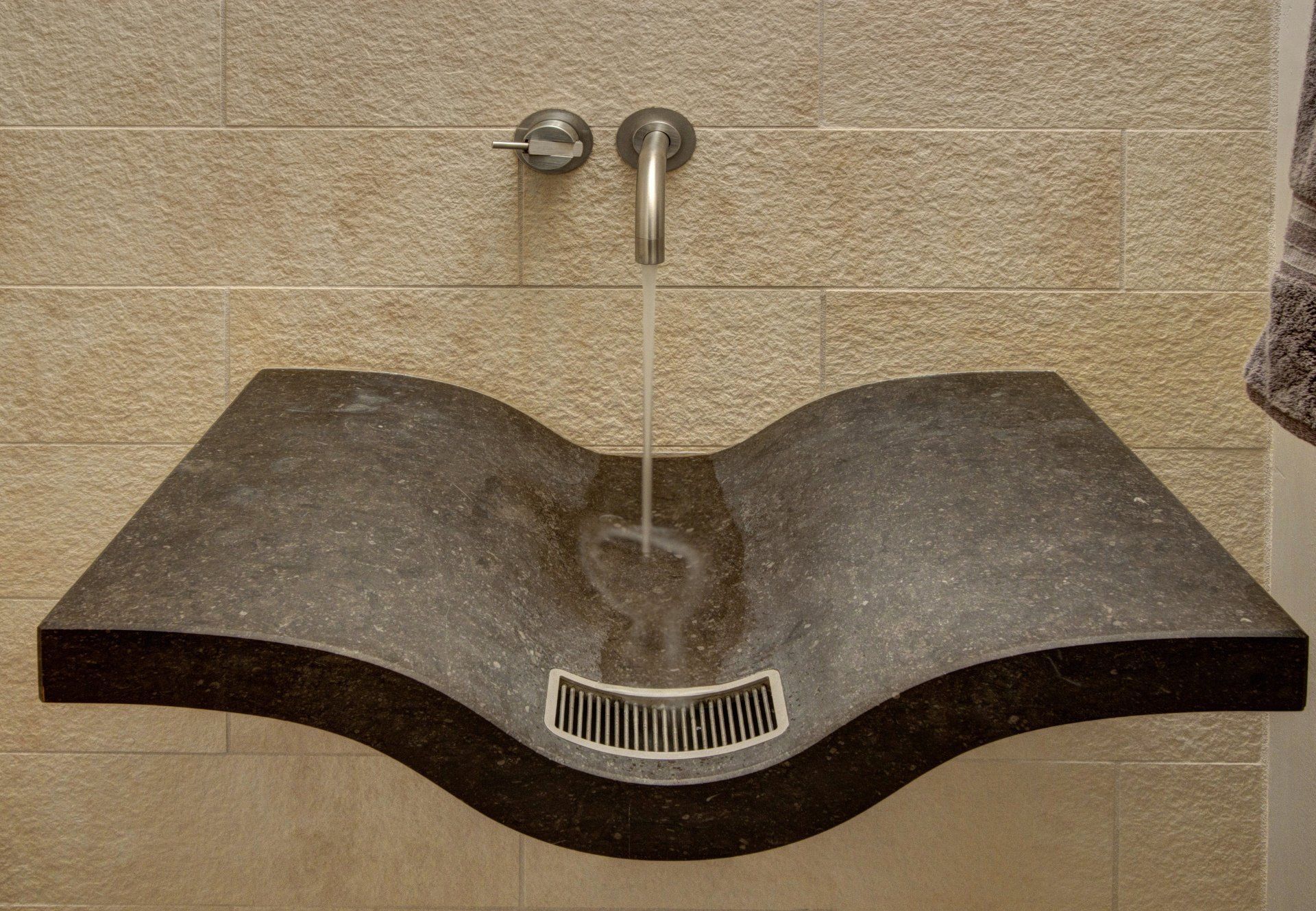 A bathroom sink that looks like a book with water coming out of it
