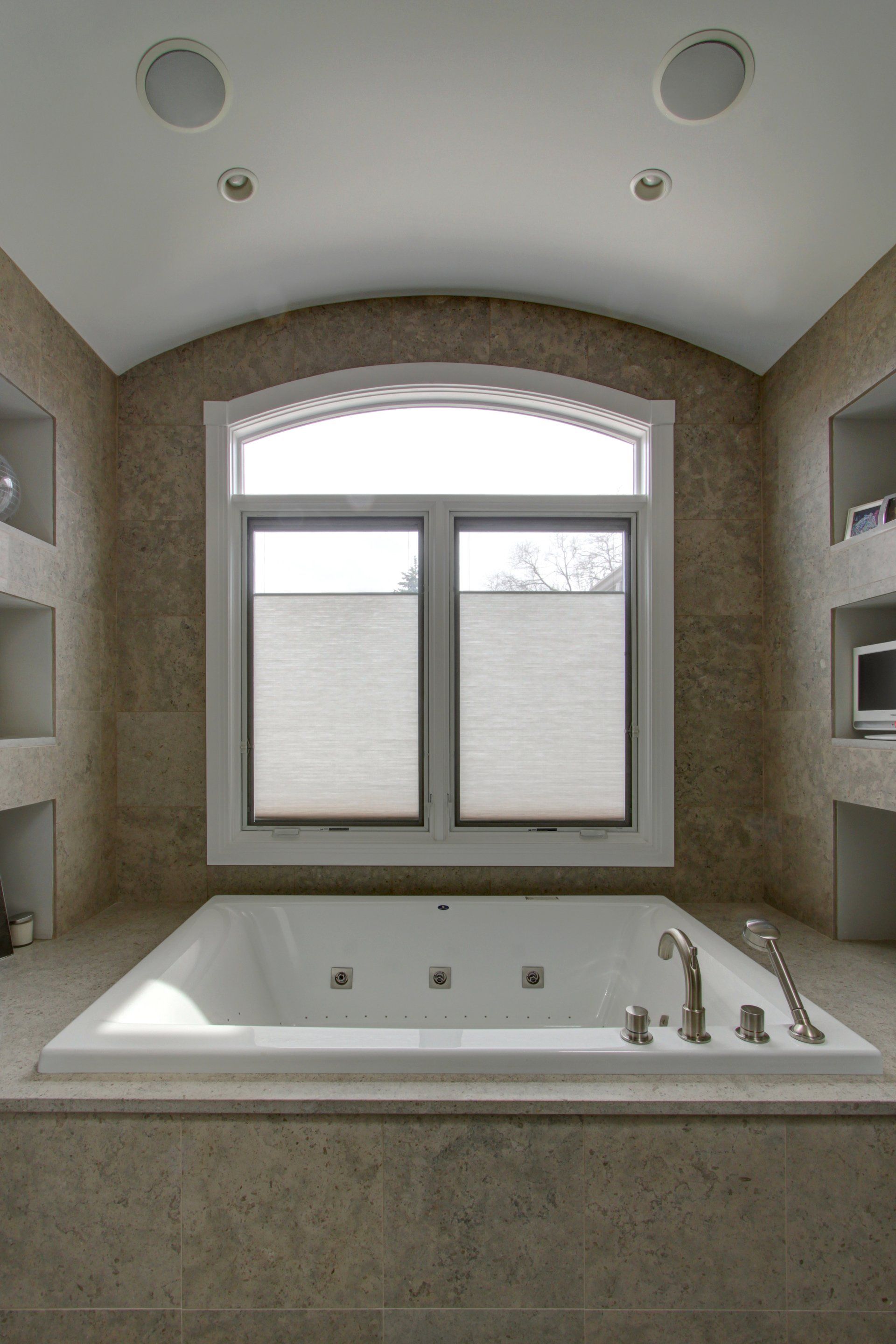 A bathroom with a jacuzzi tub and a window.
