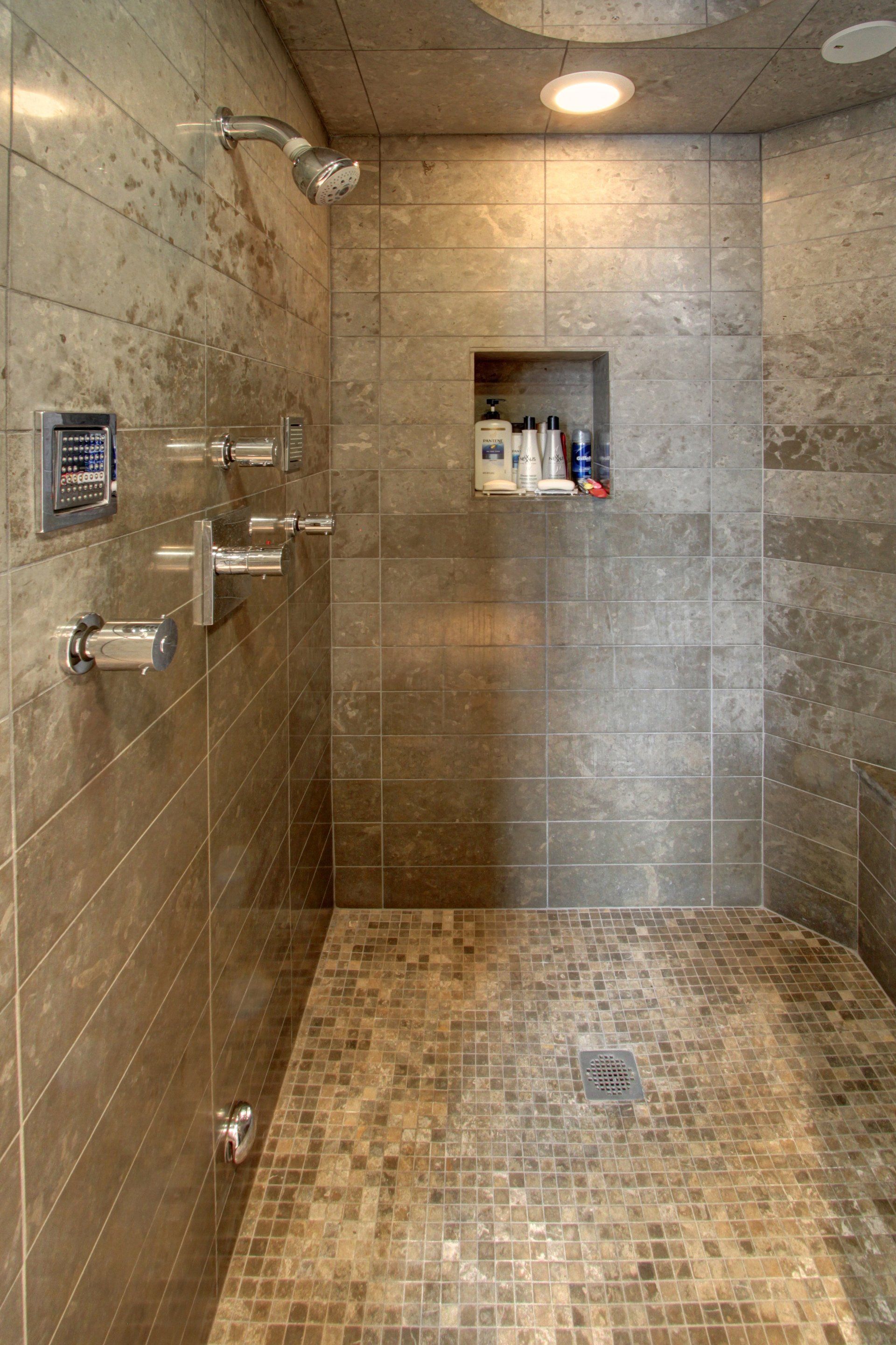A walk in shower with a tiled floor and a shower head.