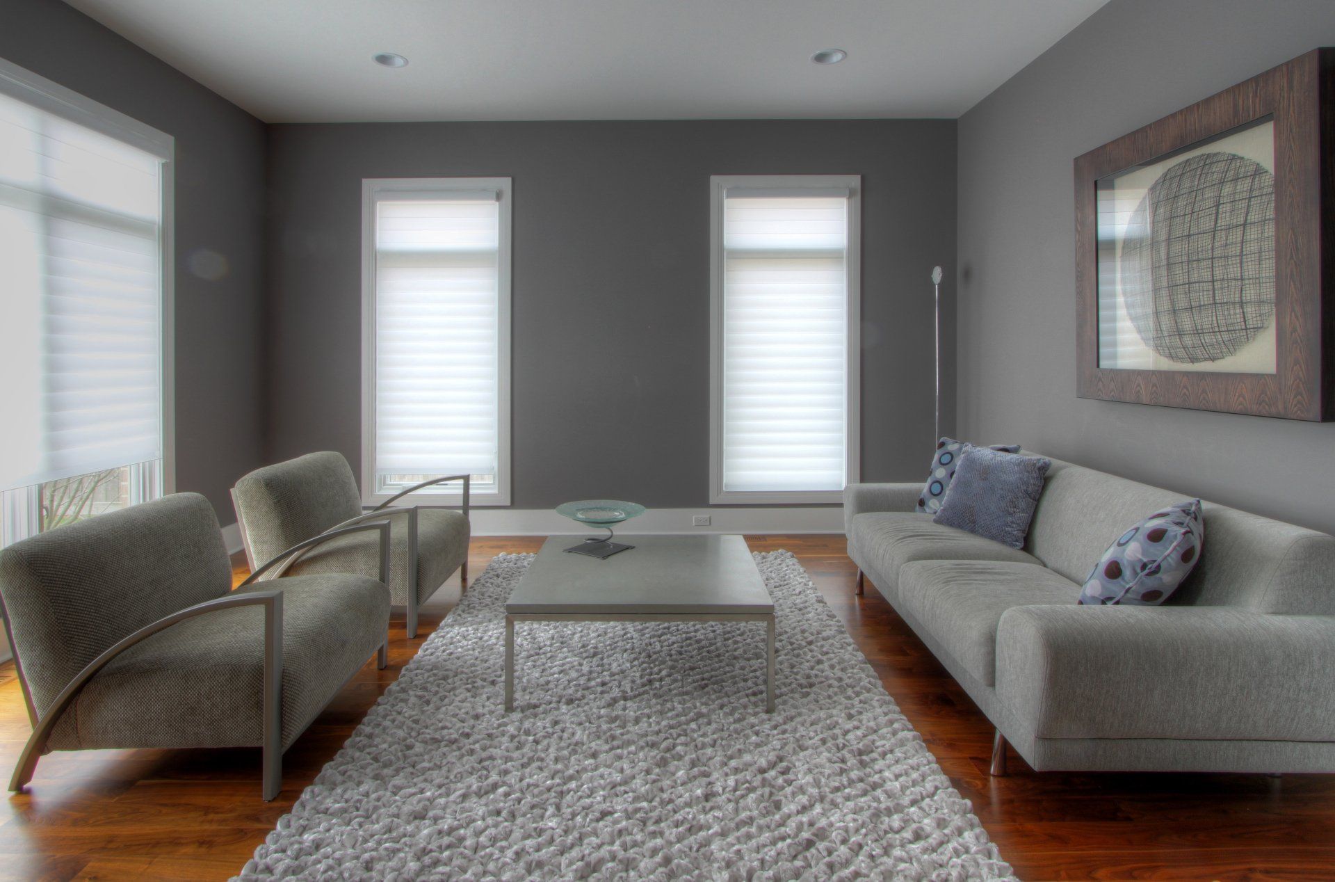 A living room with a couch , two chairs , a coffee table and a rug.