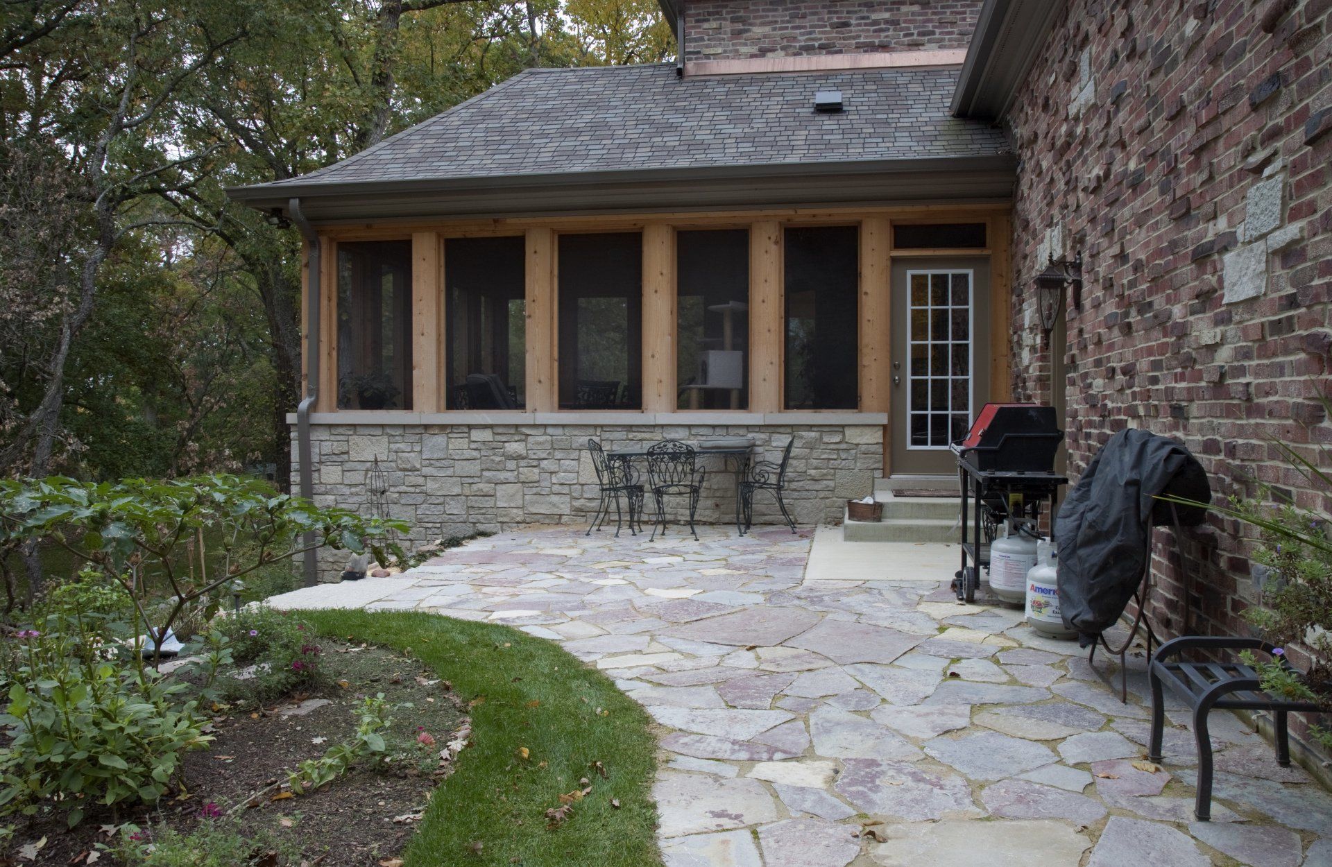 A brick house with a screened in porch and patio.