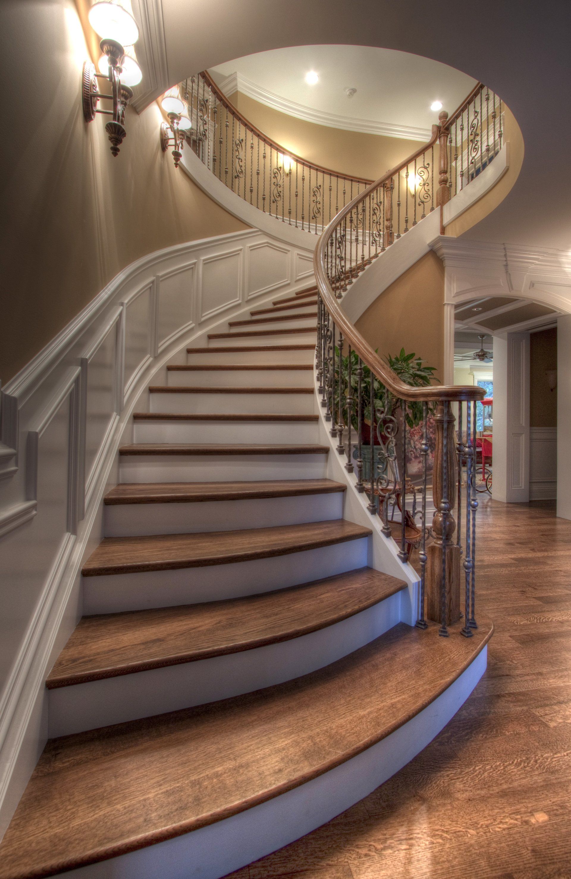 A curved staircase in a house with a wrought iron railing.