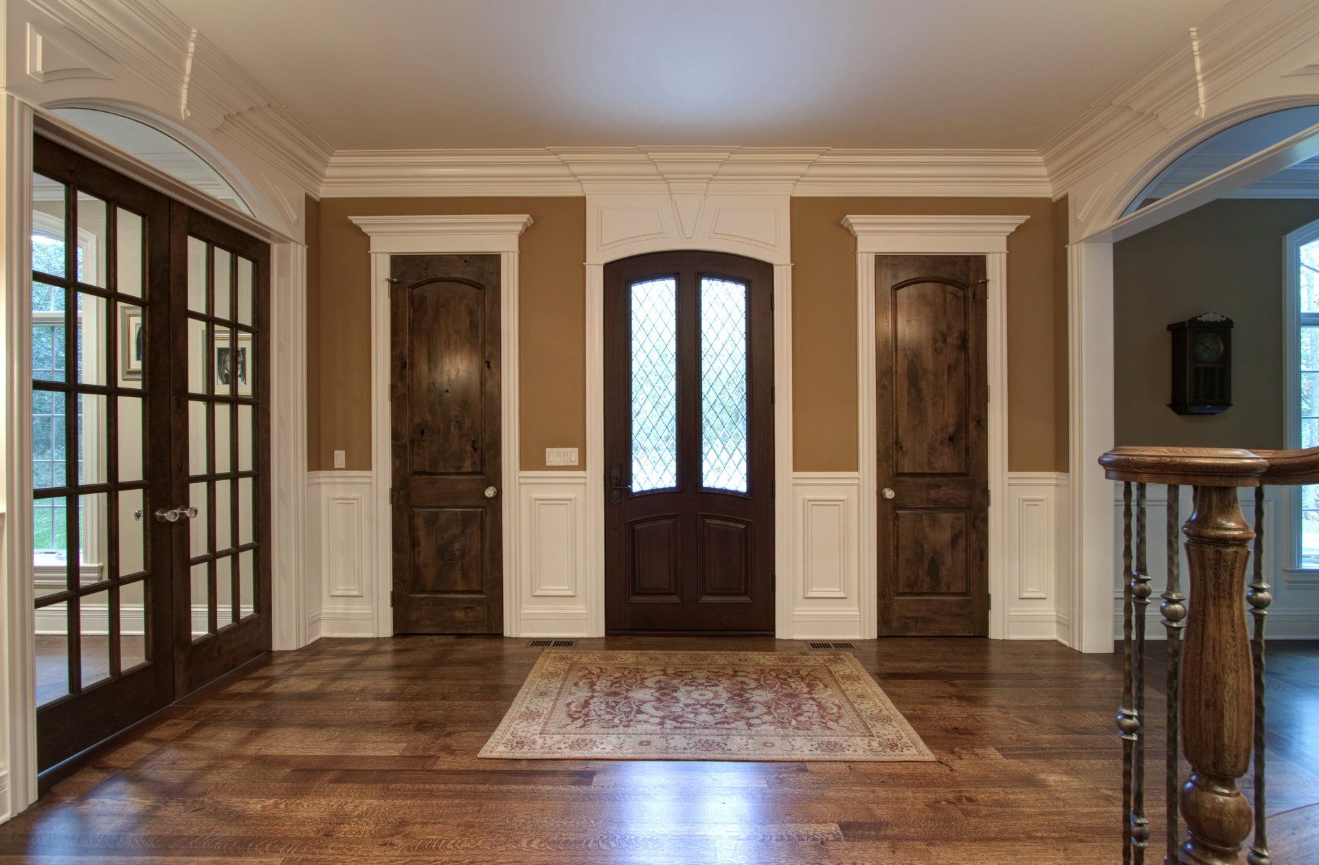A large empty hallway with hardwood floors and a staircase leading to the front door.