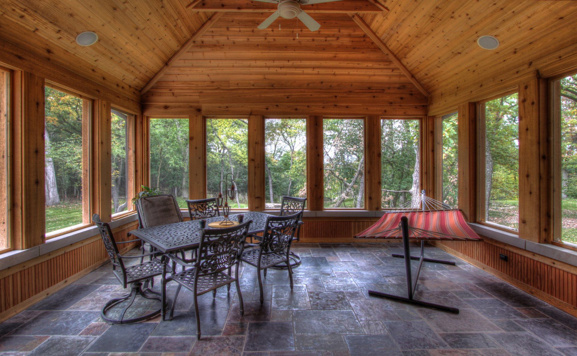 A sun room with a table and chairs and a ceiling fan.