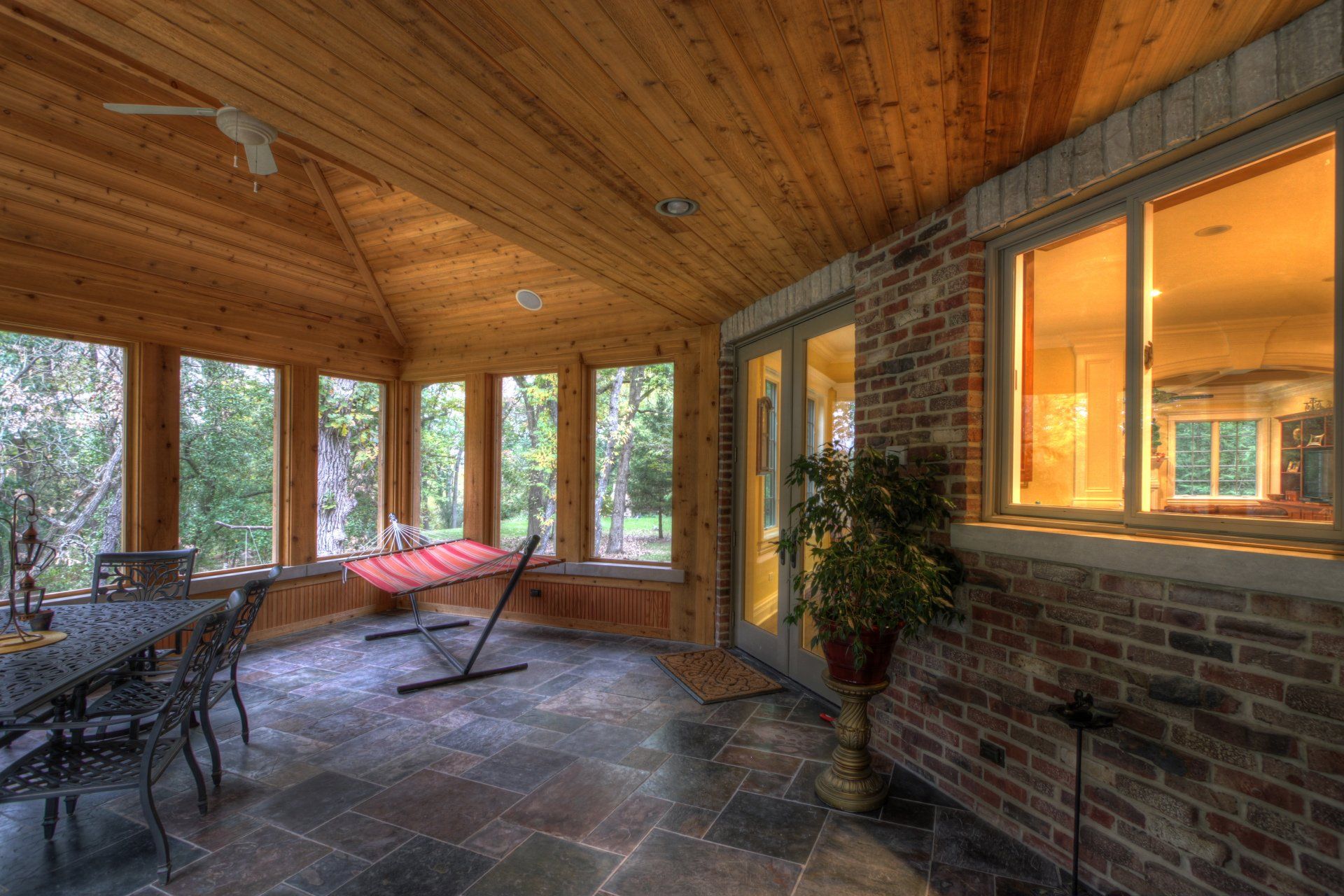 A screened in porch with a table and chairs and a hammock.