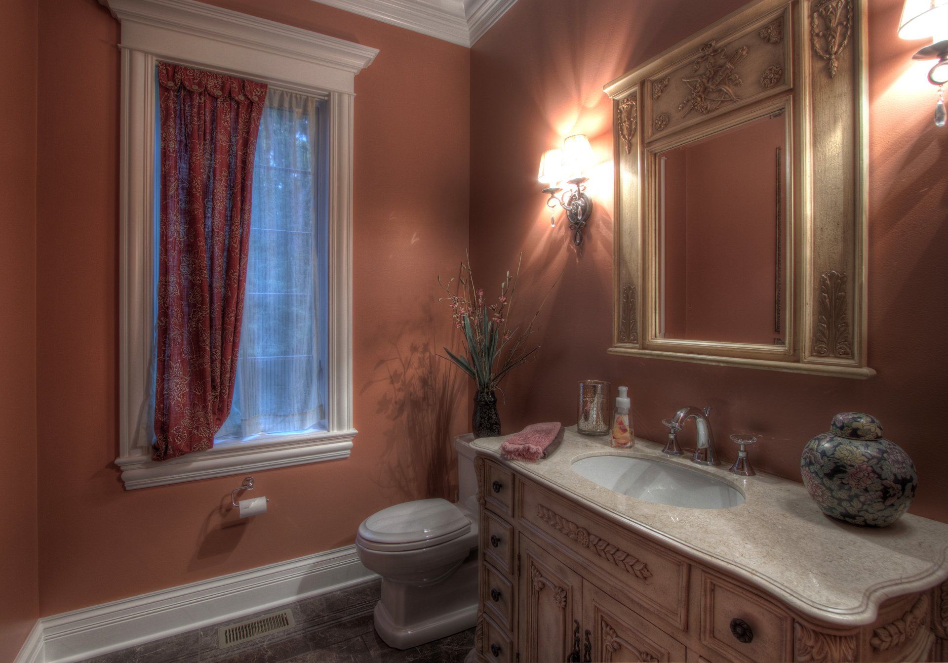 A bathroom with a toilet , sink , mirror and window.