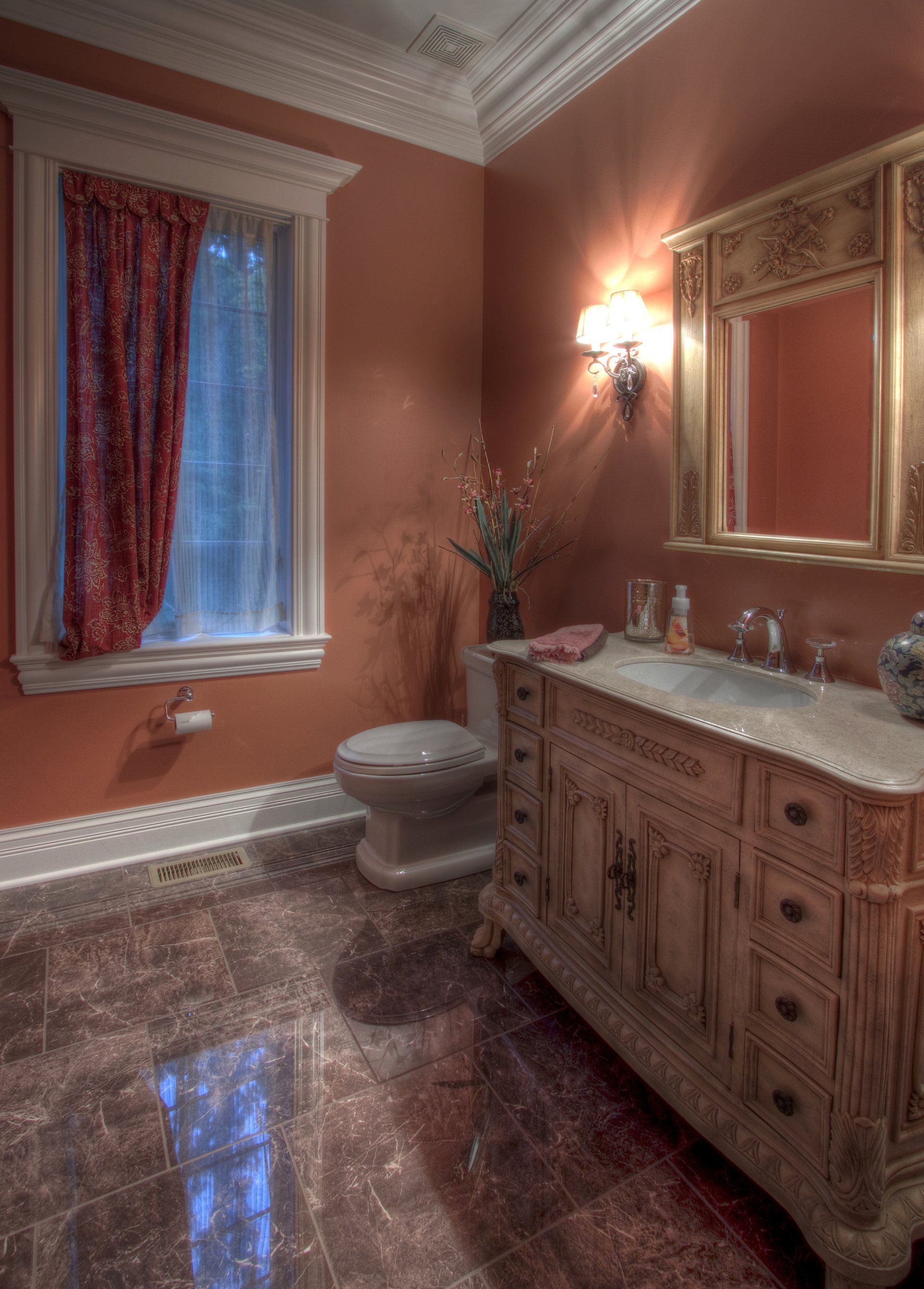 A bathroom with a toilet , sink , mirror and window