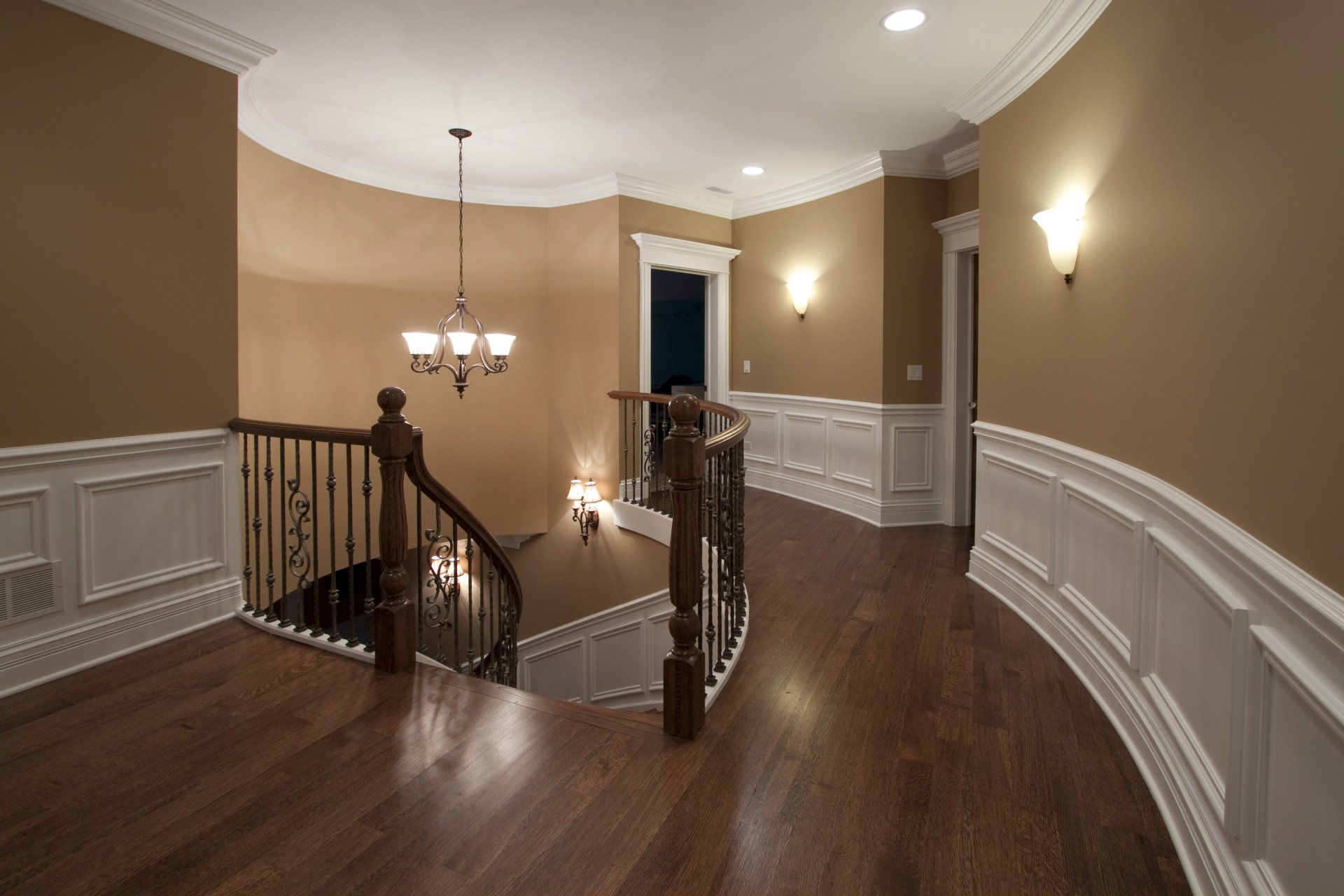 A hallway with a staircase and a chandelier hanging from the ceiling