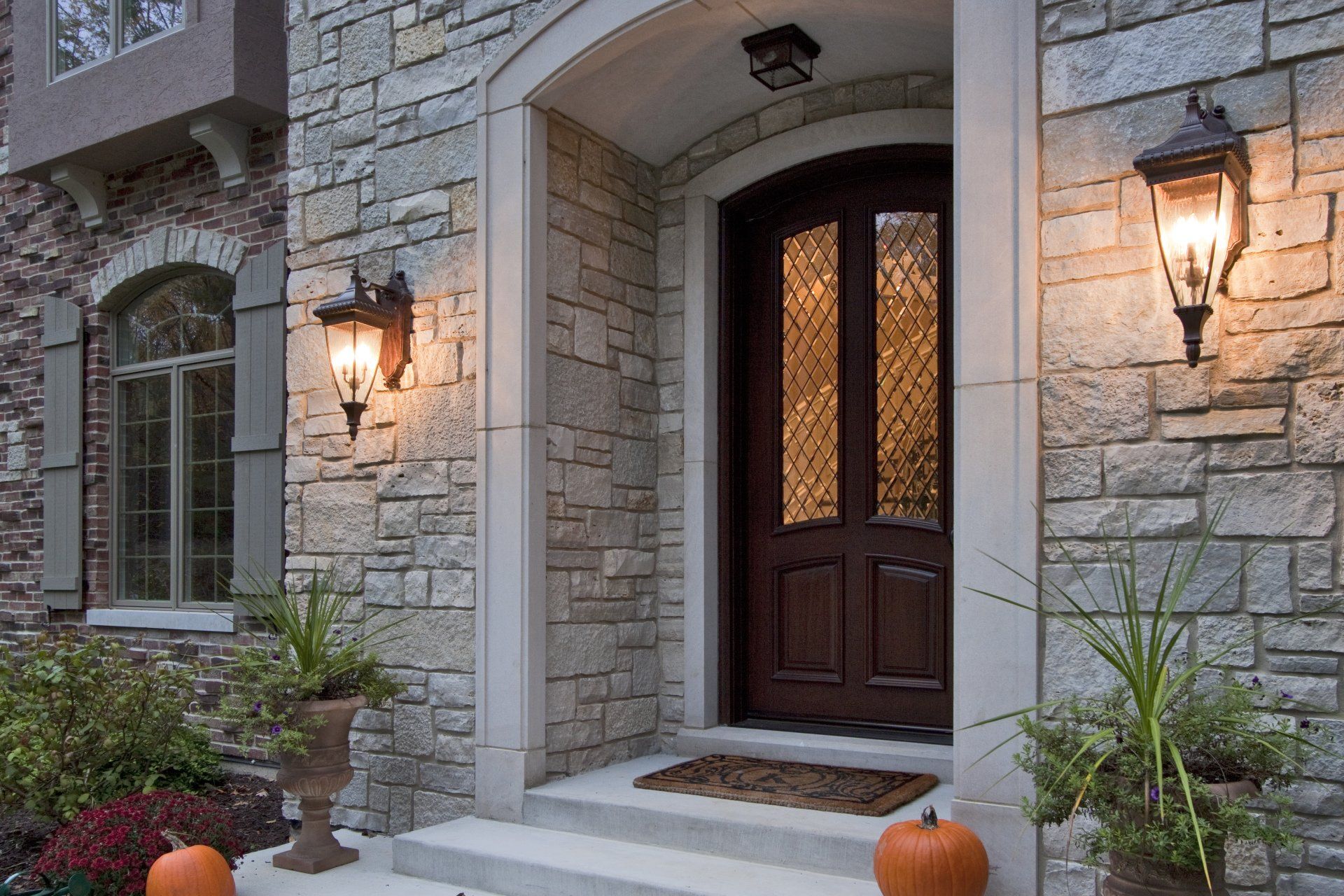 The front door of a stone house with pumpkins in front of it