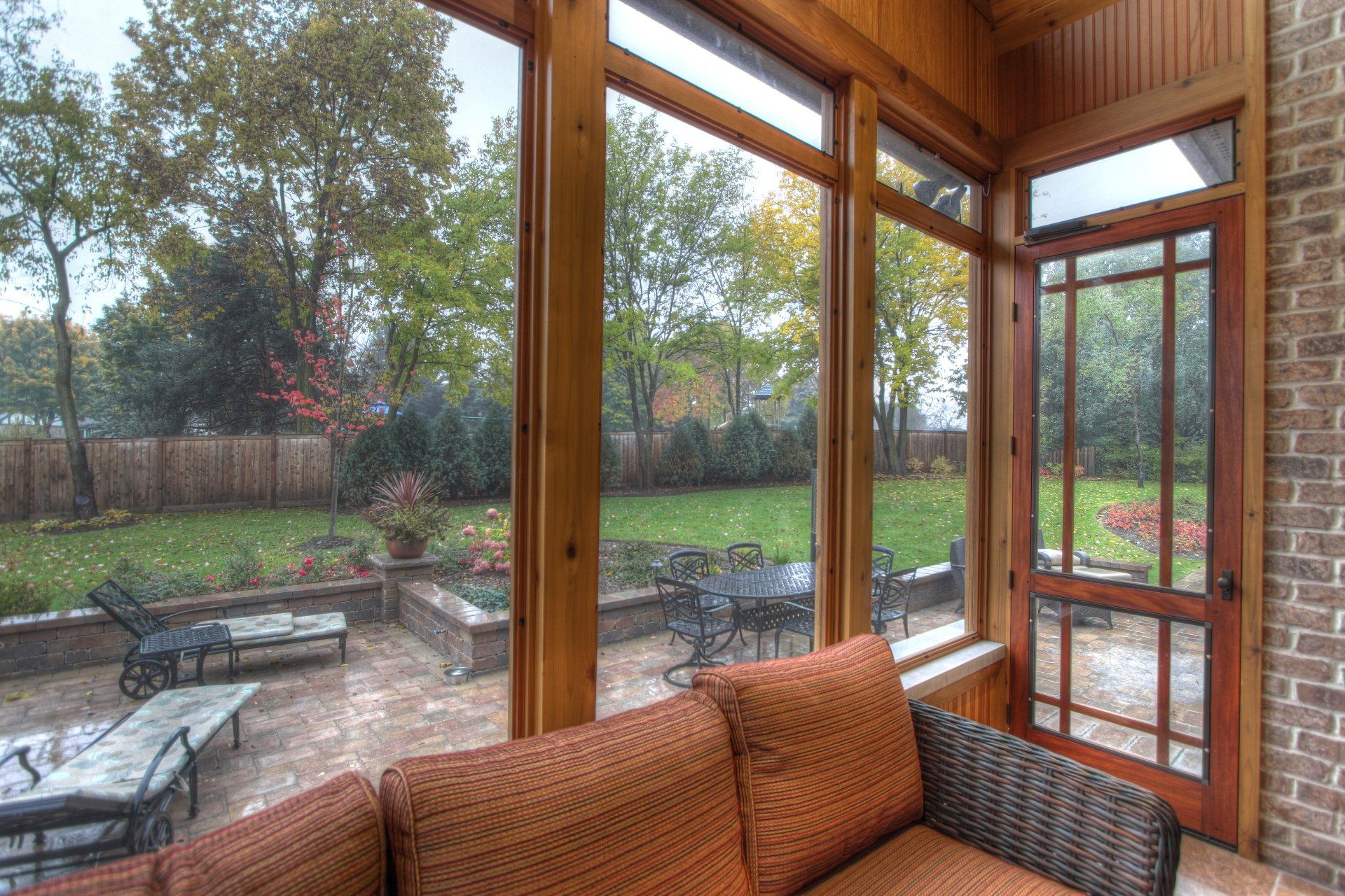 A screened in porch with a couch and chairs and a view of the backyard.