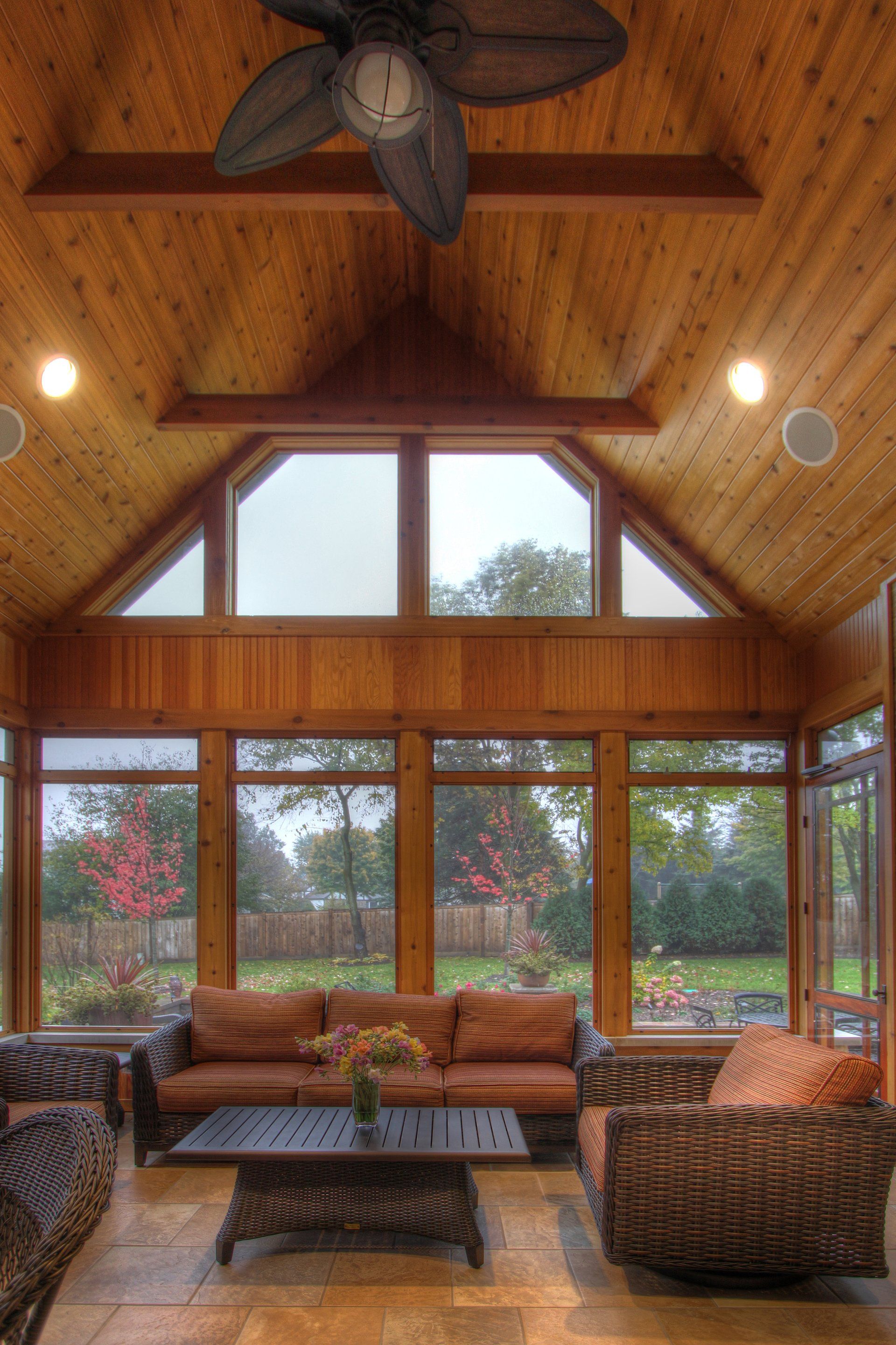 A living room with a lot of windows and a ceiling fan.