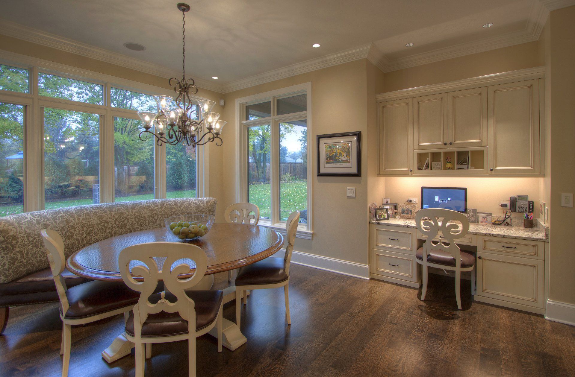 A dining room with a table and chairs and a desk.