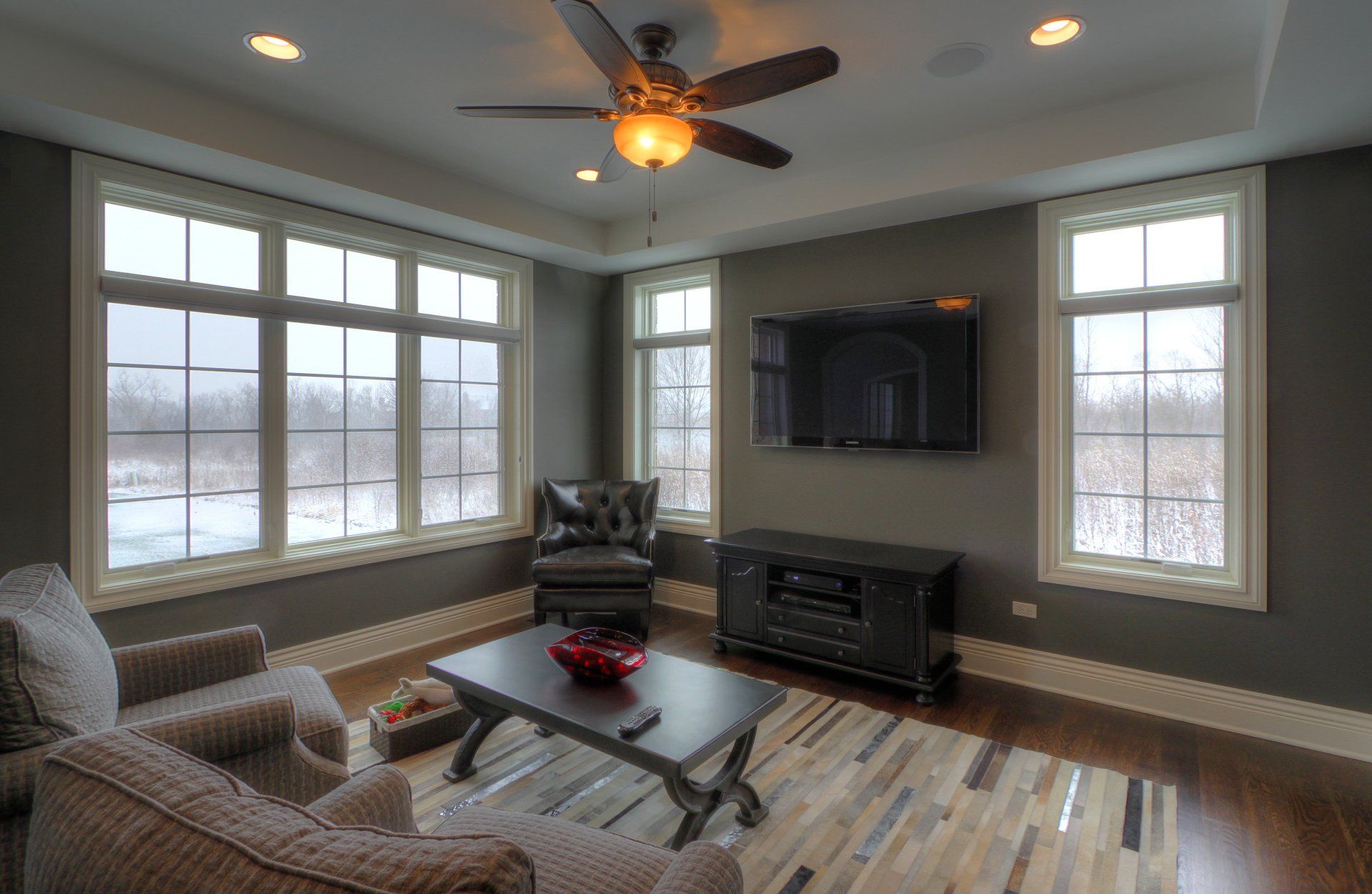 A living room with a ceiling fan and a flat screen tv.