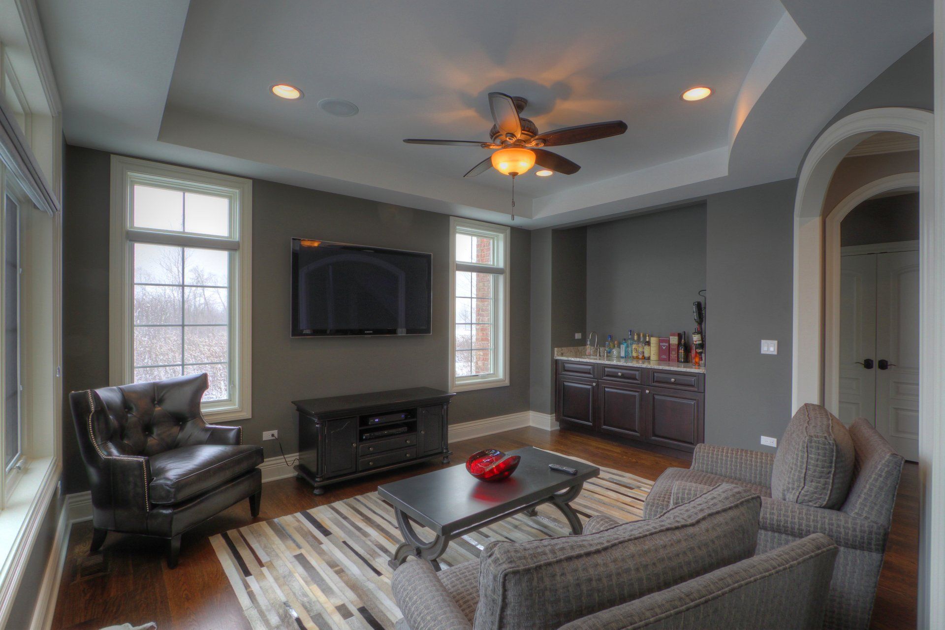 A living room with a ceiling fan and a flat screen tv