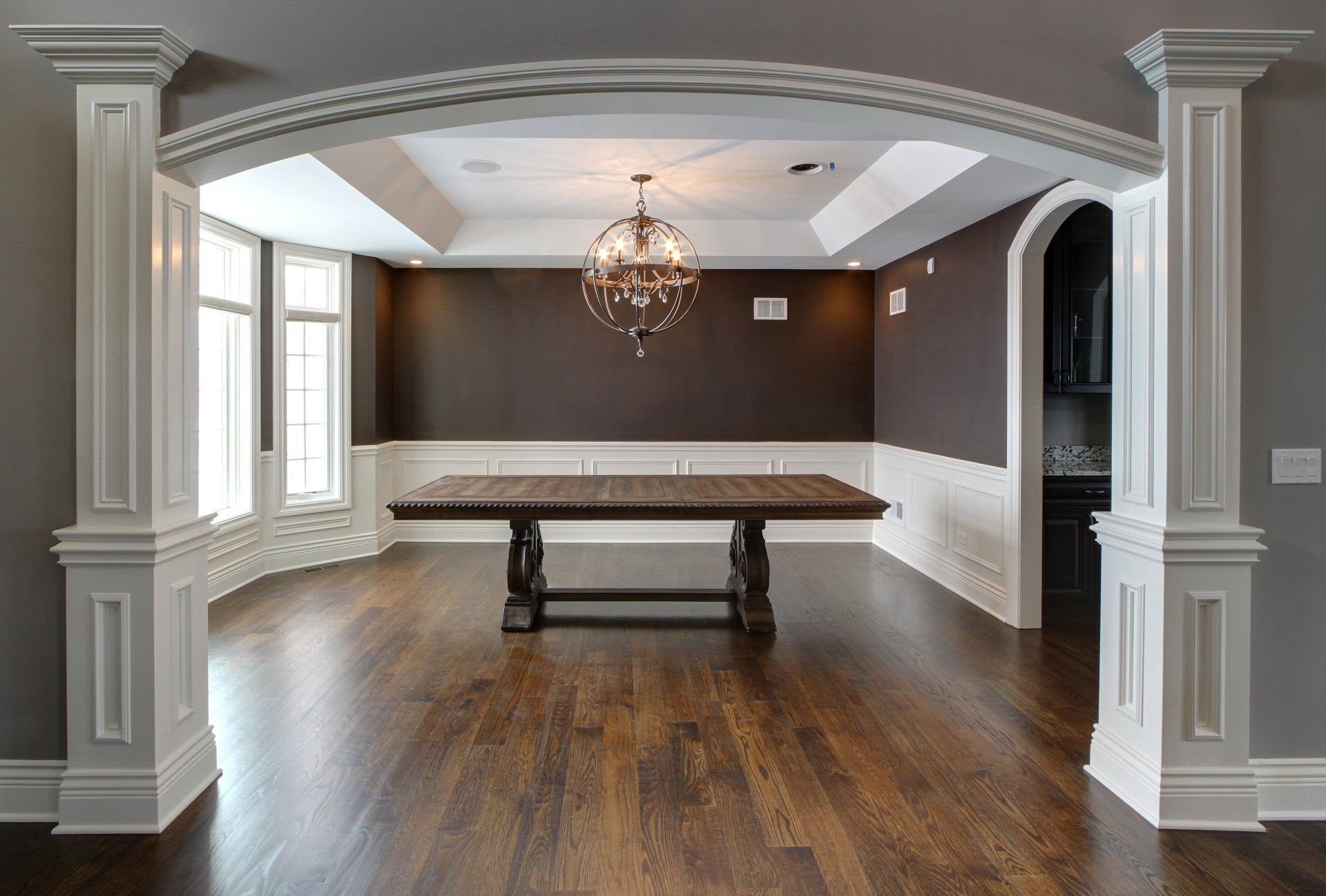 An empty dining room with a wooden table and columns