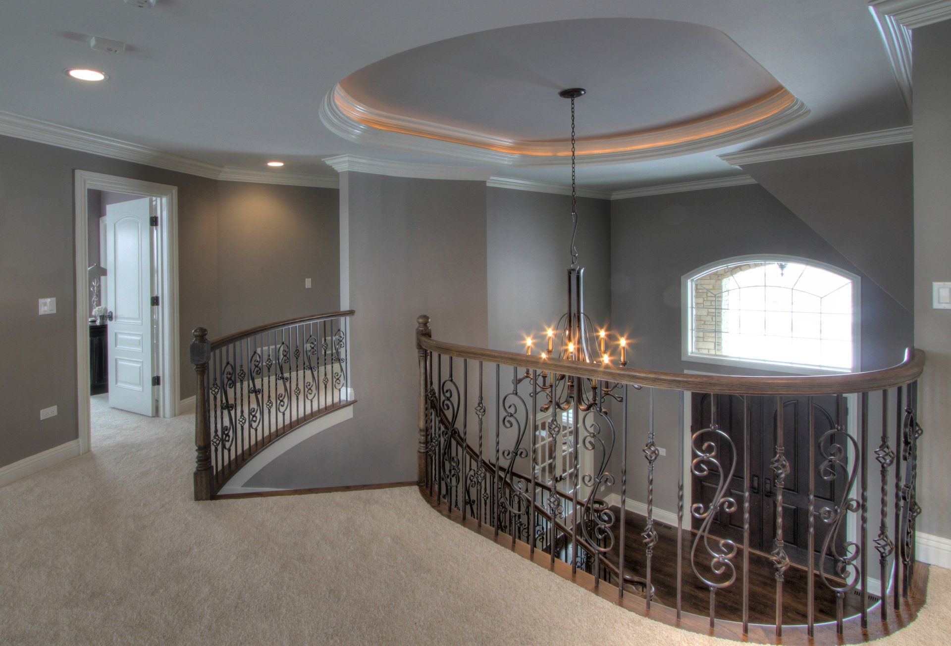 A staircase with a wrought iron railing and a chandelier hanging from the ceiling