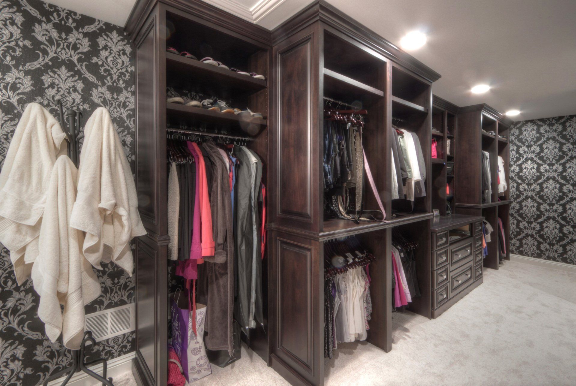 A walk in closet with a lot of clothes and towels