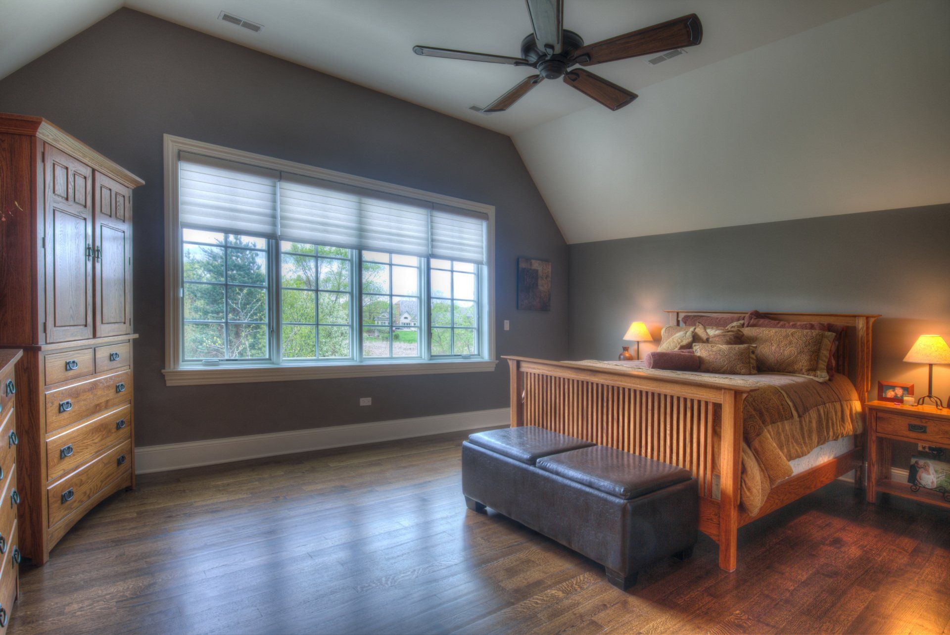 A bedroom with a ceiling fan and a large bed