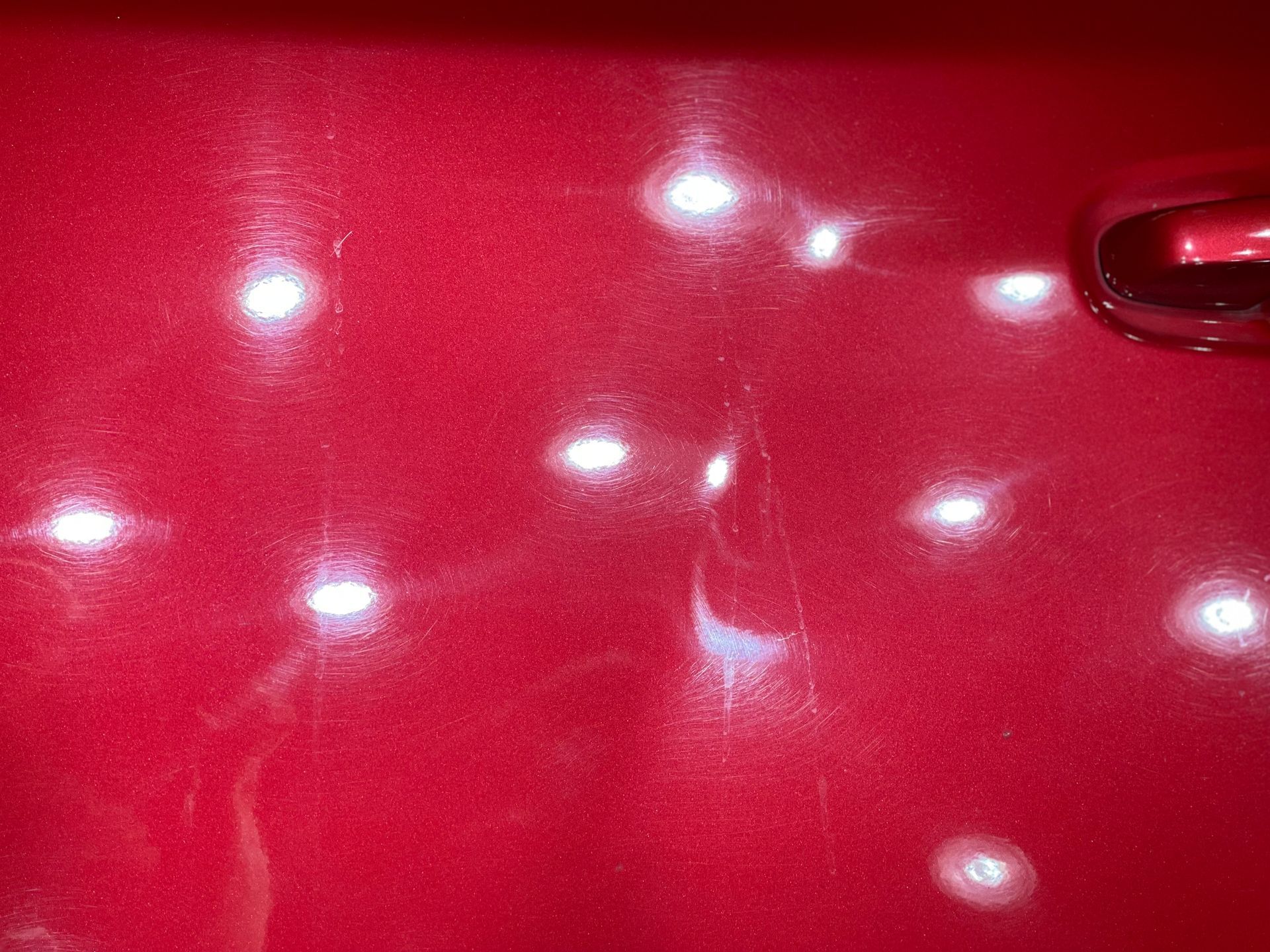 a close up of a red car door with white spots on it .