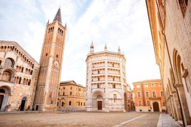 Parma, piazza con alto campanile e battistero. Giornata di sole.