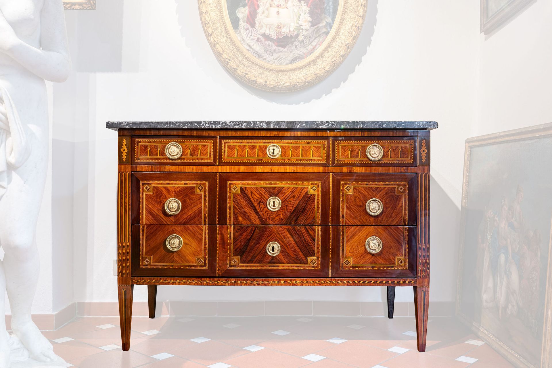 Una cassettiera di legno è posta in una stanza con una statua sullo sfondo.