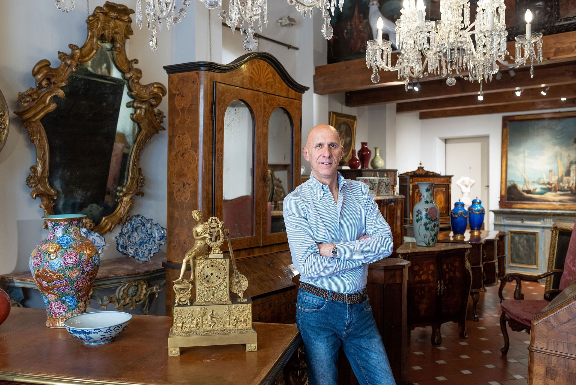 Un uomo è in piedi in un negozio di antiquariato con le braccia incrociate.