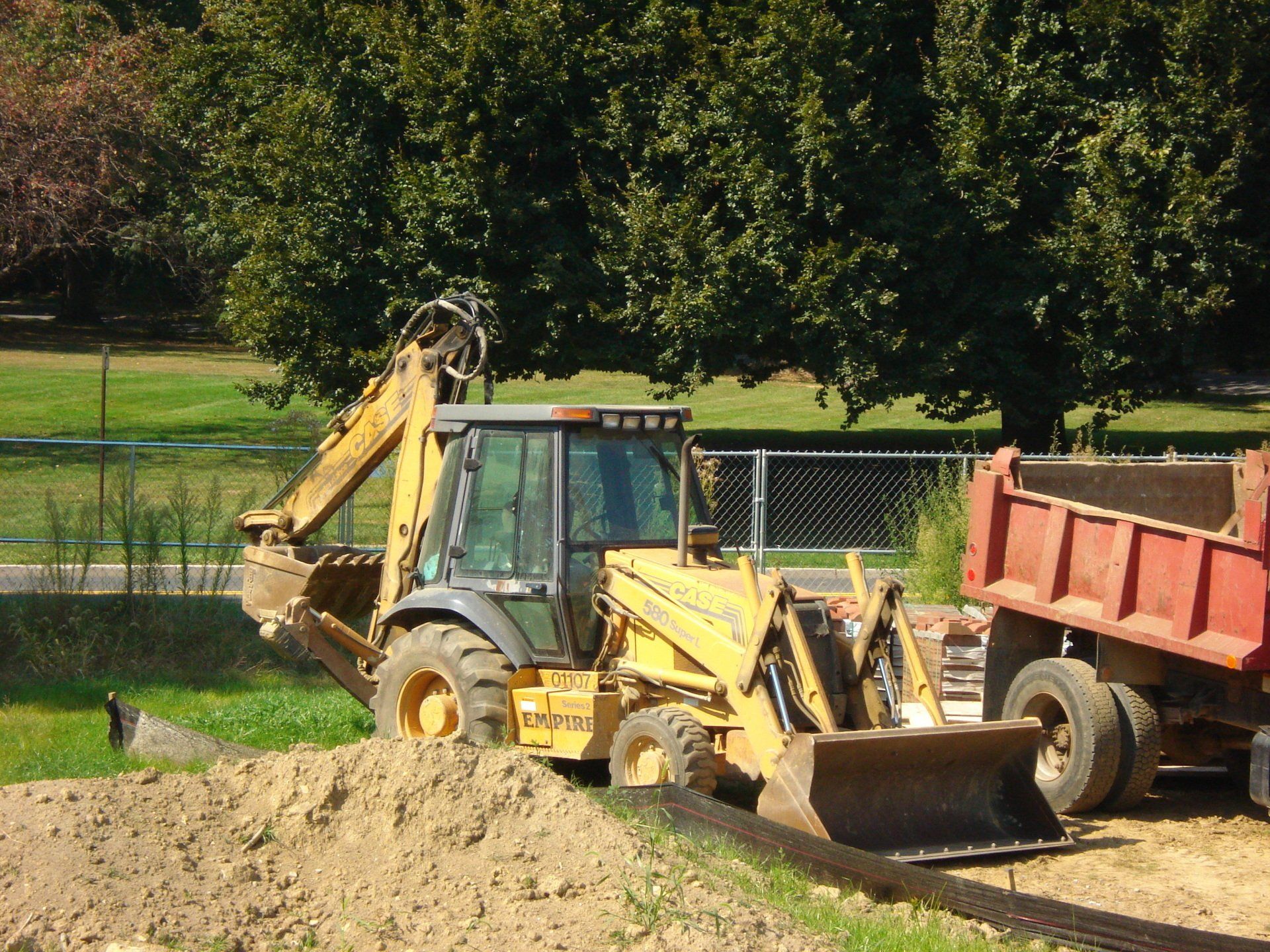 A bulldozer is loading dirt into a dump truck