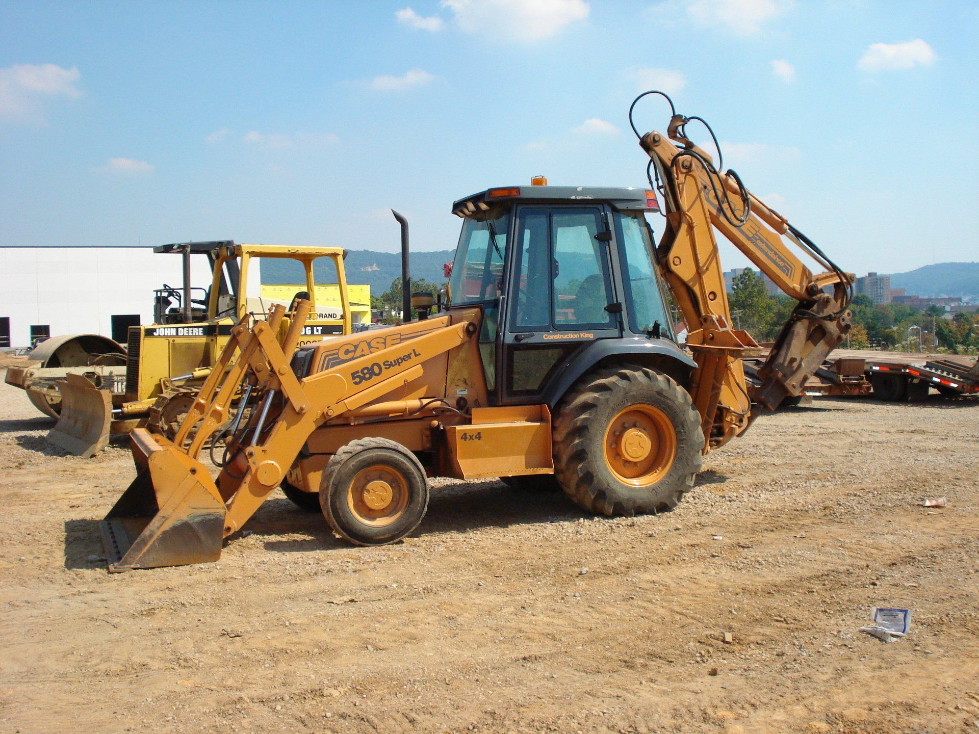A yellow case backhoe is parked in a dirt field