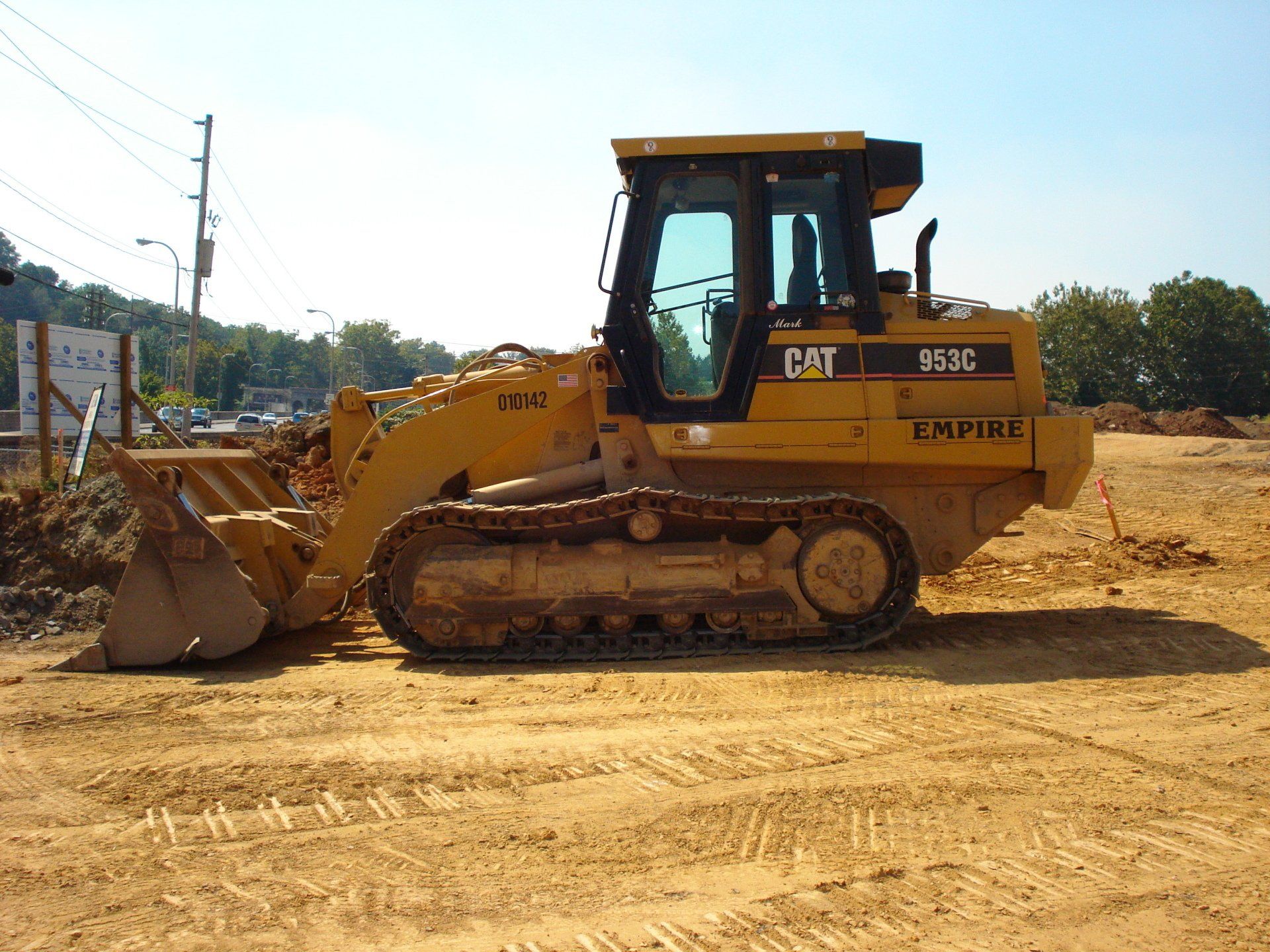 A yellow cat bulldozer is parked in a dirt field