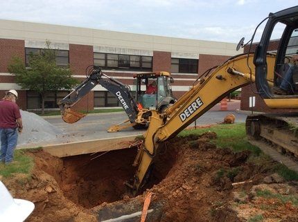 A deere excavator is digging a hole in the ground