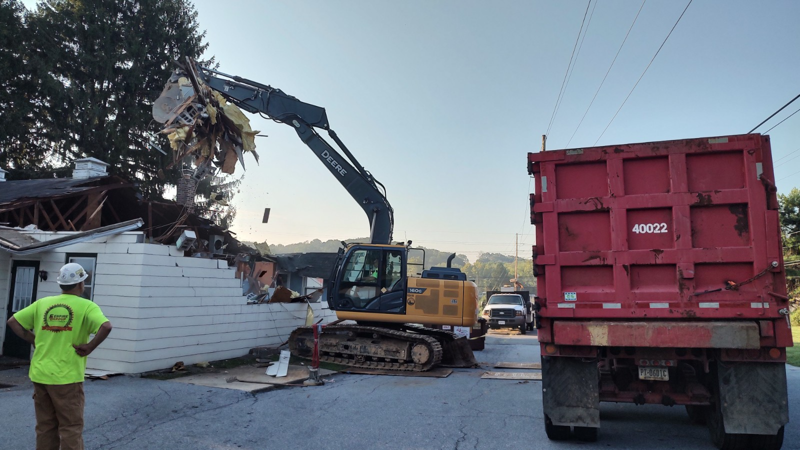 A bulldozer is demolishing a building next to a dump truck.