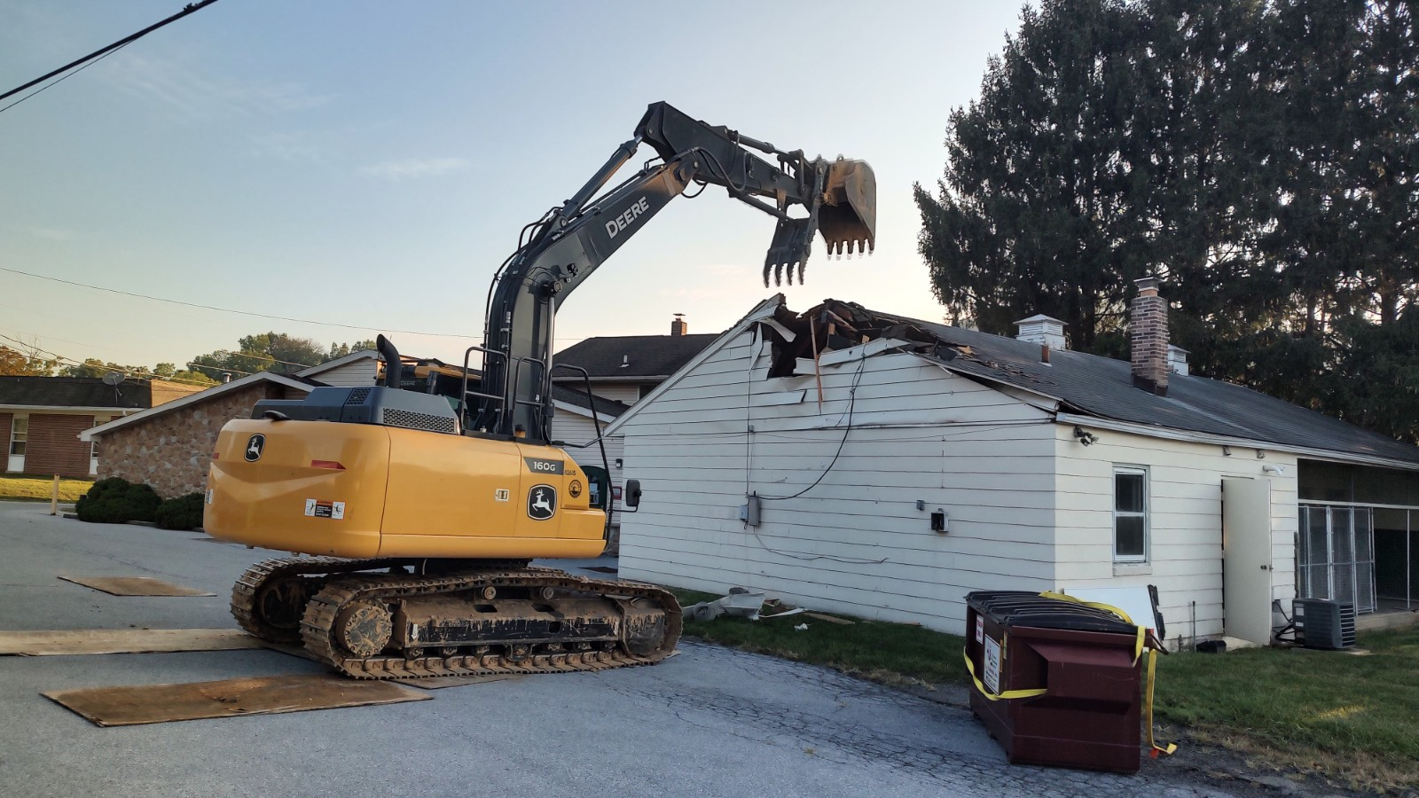 A yellow excavator is demolishing a white house.