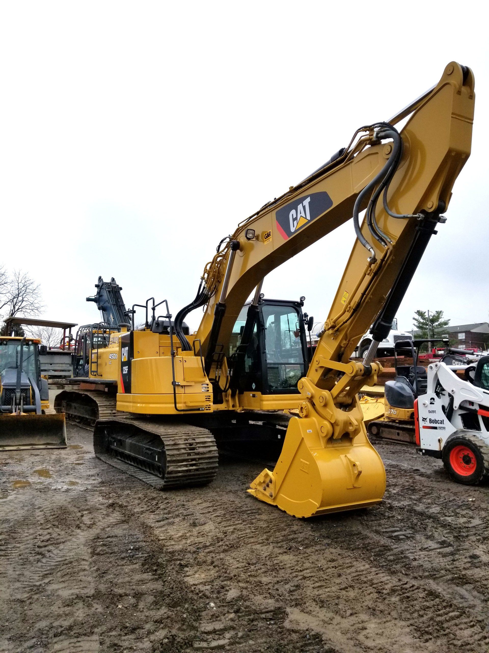 A large yellow excavator is parked in a dirt lot.