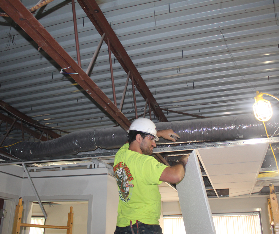 Start of a Bank Renovation for Empire Services. A team member removes ceiling tiles.