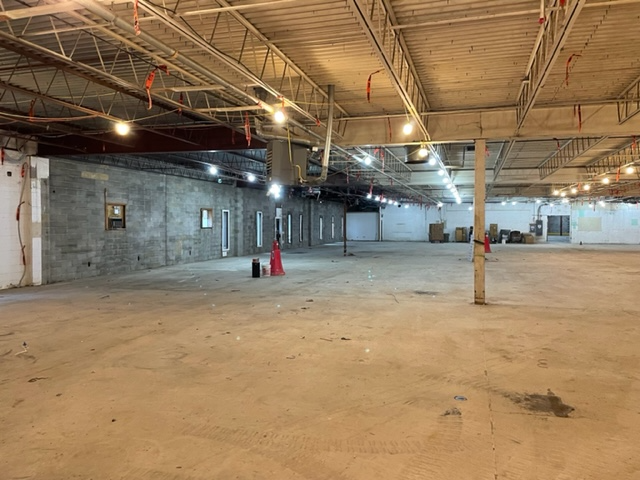 A large empty warehouse with a lot of lights on the ceiling.