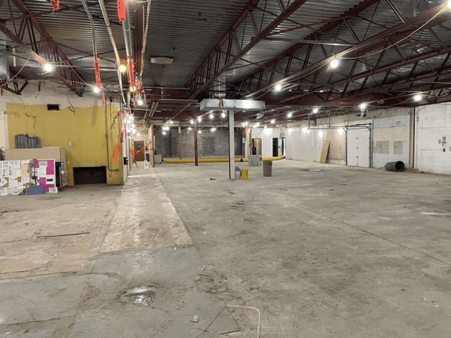 A large empty warehouse with a lot of lights on the ceiling.
