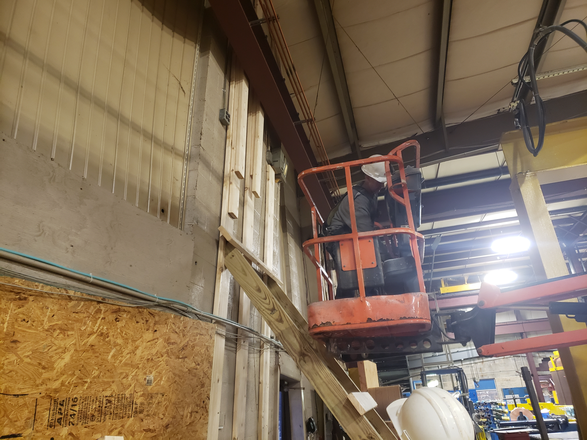 A man in a lift is working on a wall in a building.
