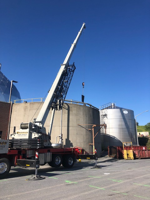 A large crane is parked in front of a large tank
