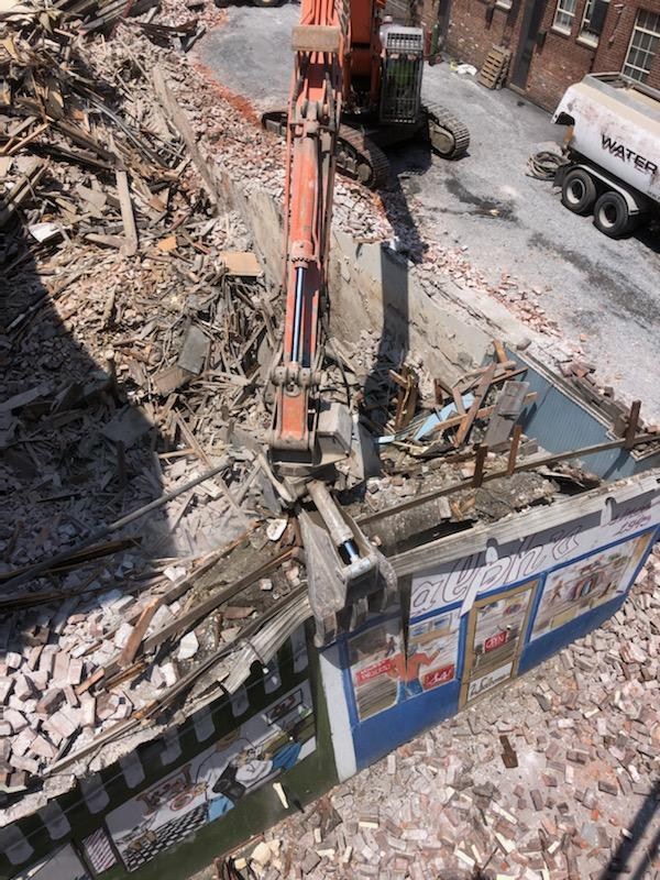 A large excavator is demolishing a building in a city.