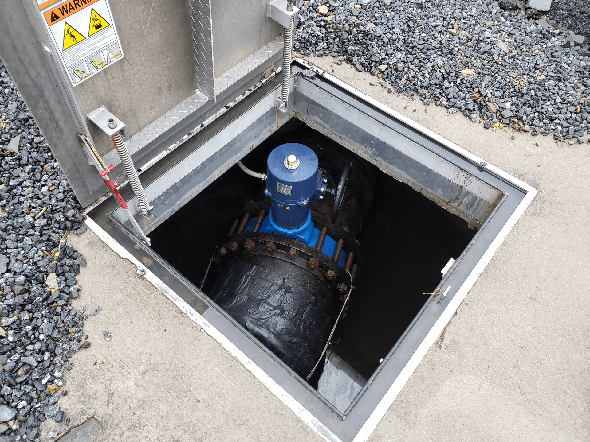 A blue pipe is sitting in a manhole cover.