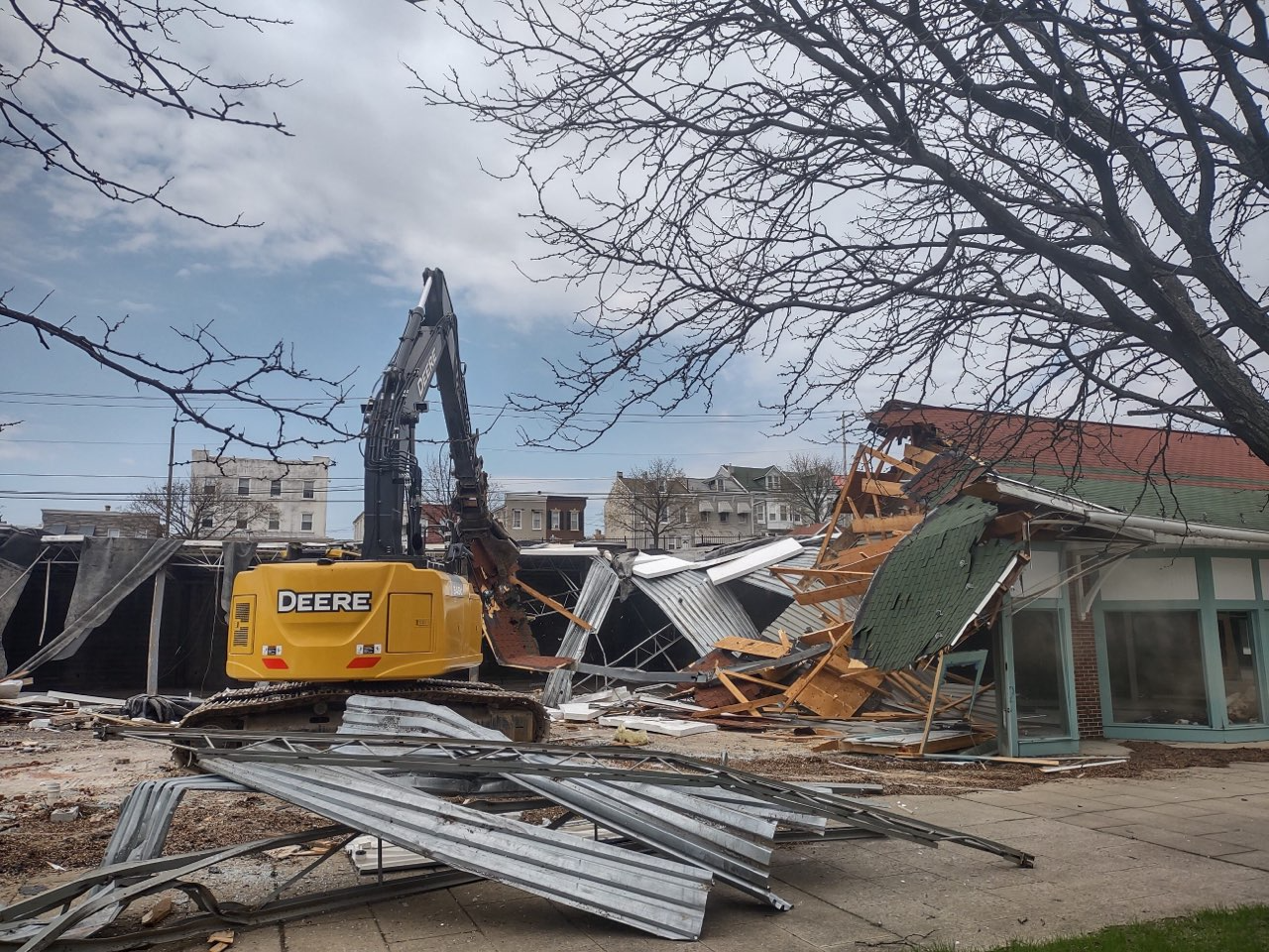 A yellow deere excavator is demolishing a building