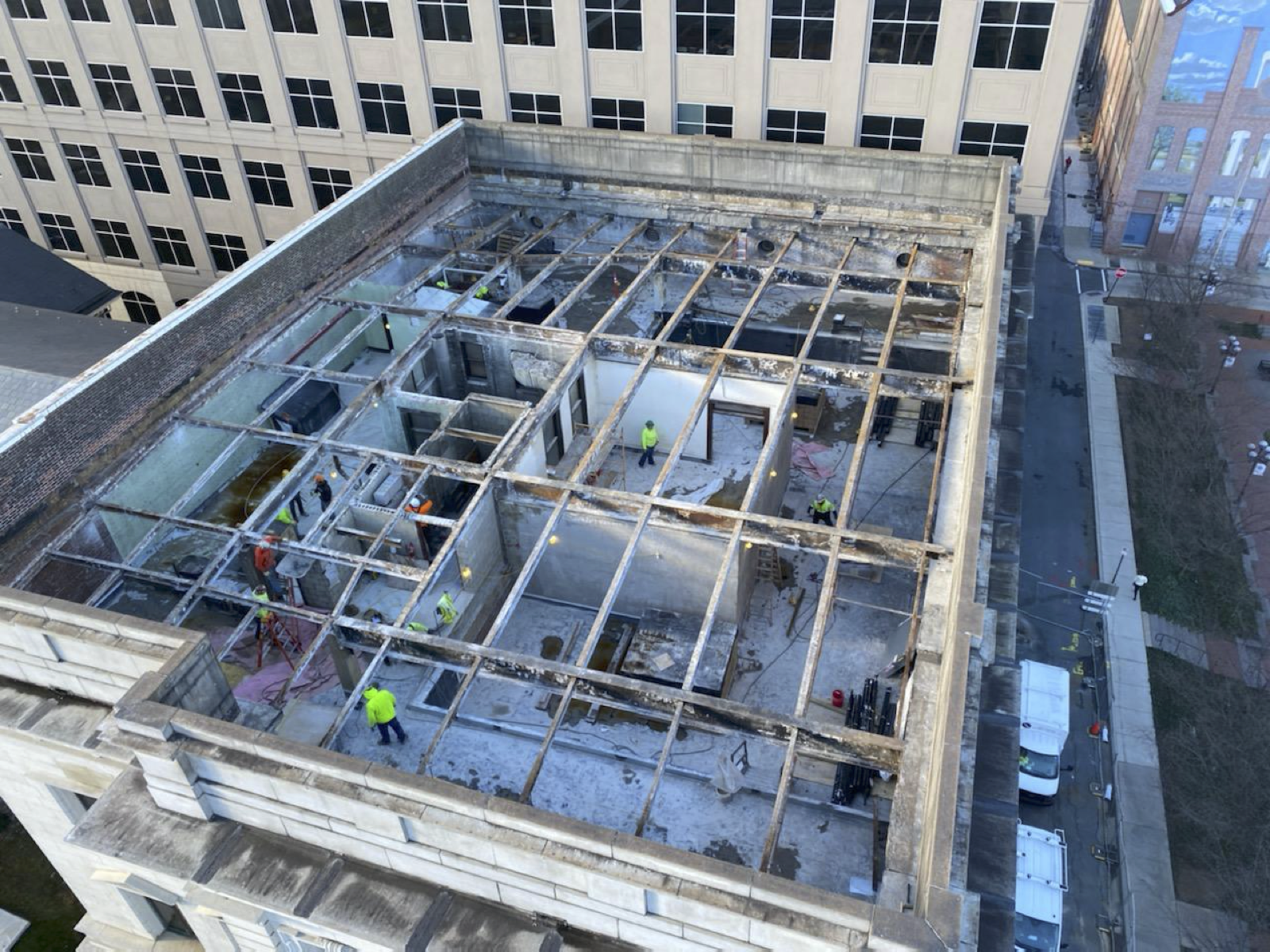 An aerial view of a building under construction with workers on the roof.