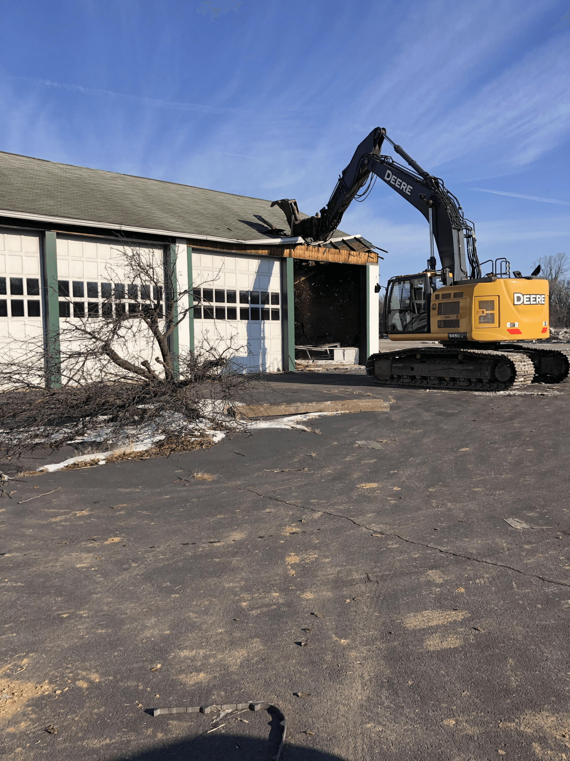 A large yellow excavator is demolishing a building.