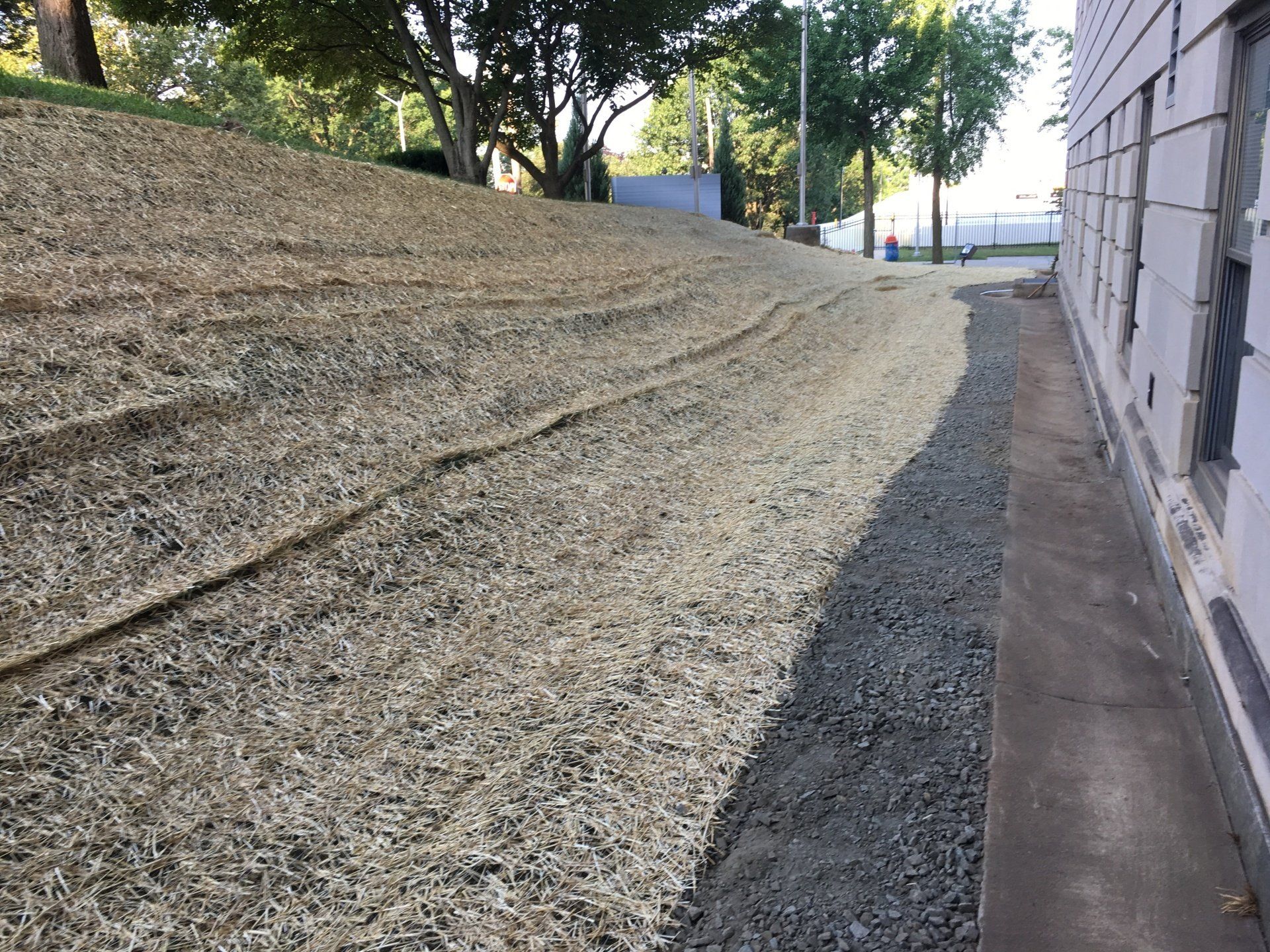 A gravel driveway leading to a building with trees in the background.