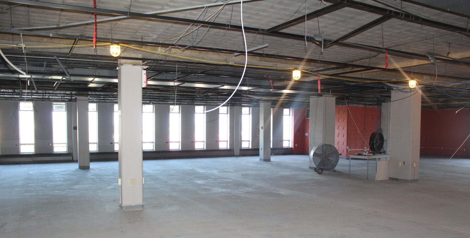 A large empty room with a lot of wires hanging from the ceiling.