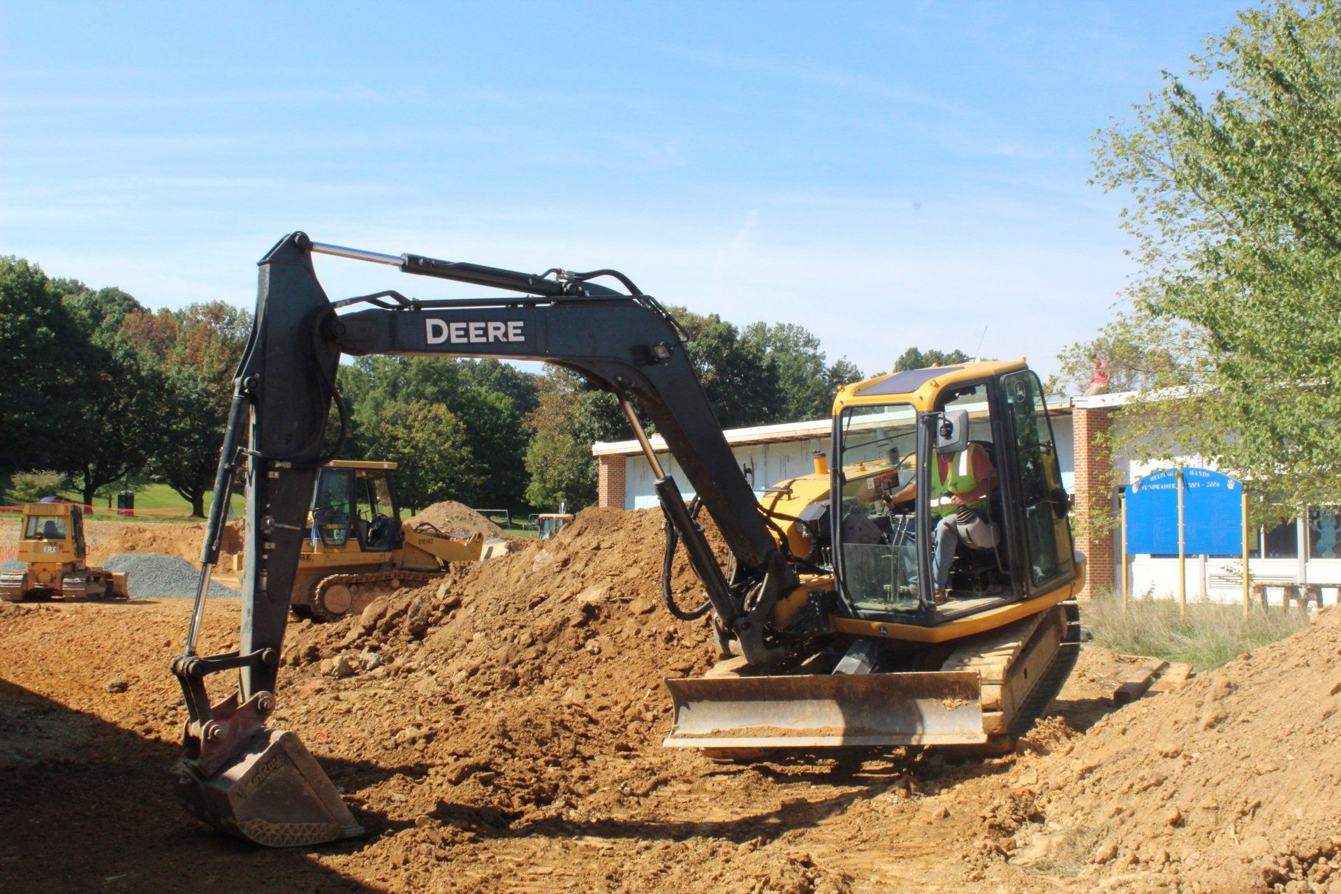 A deere excavator is digging a hole in the dirt