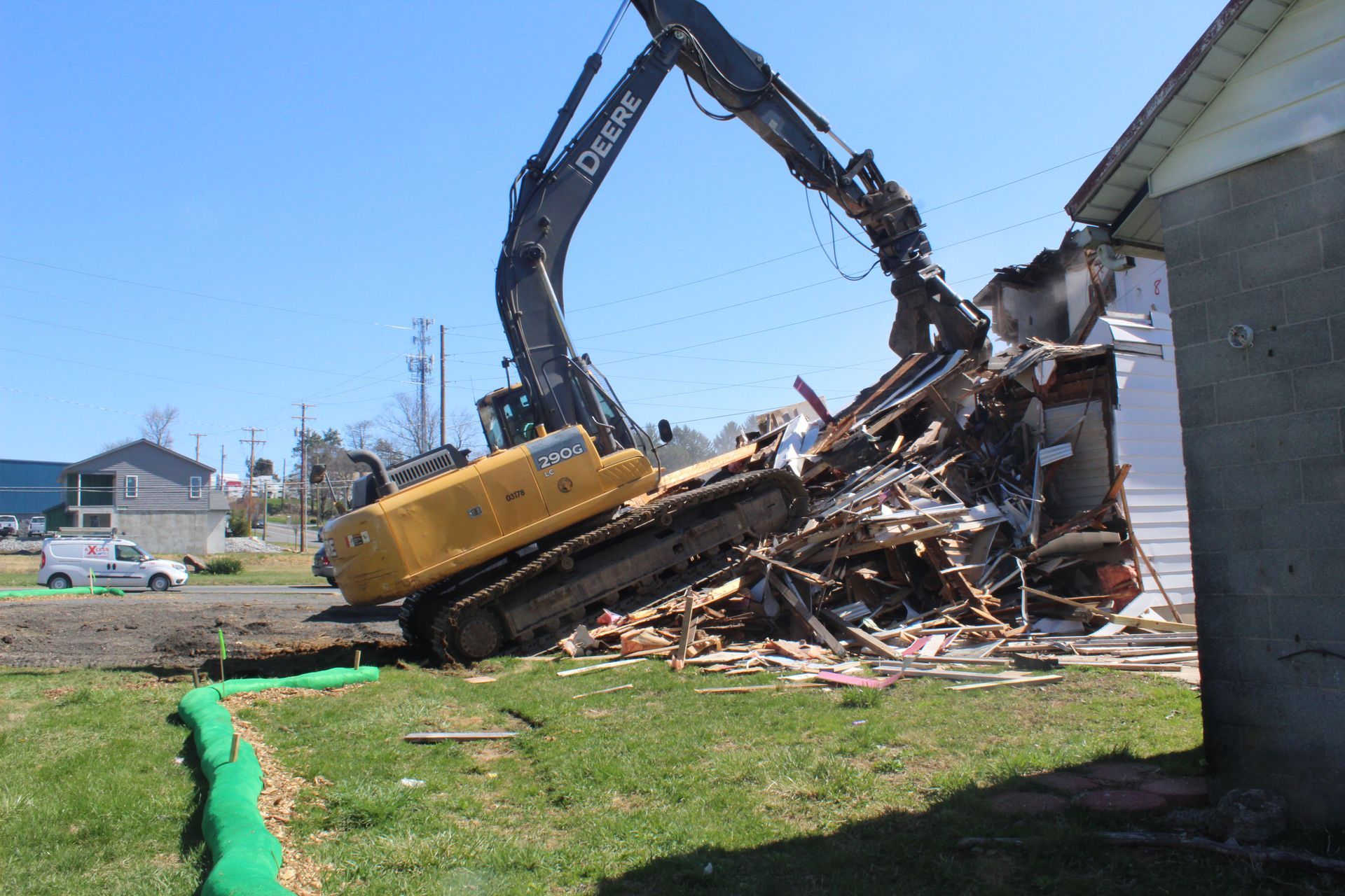 A large deere excavator is demolishing a house