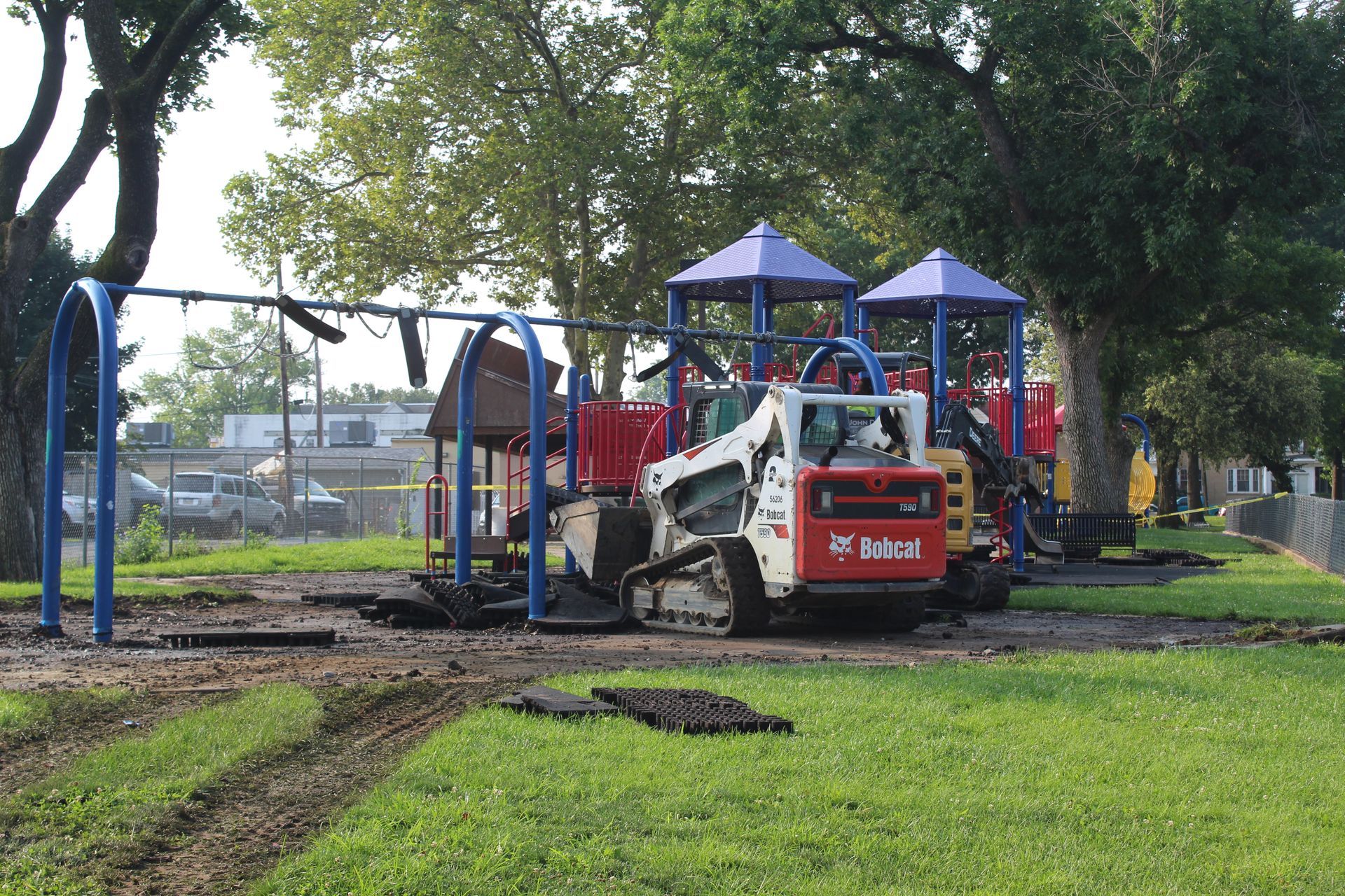A bobcat tractor is parked in front of a playground.