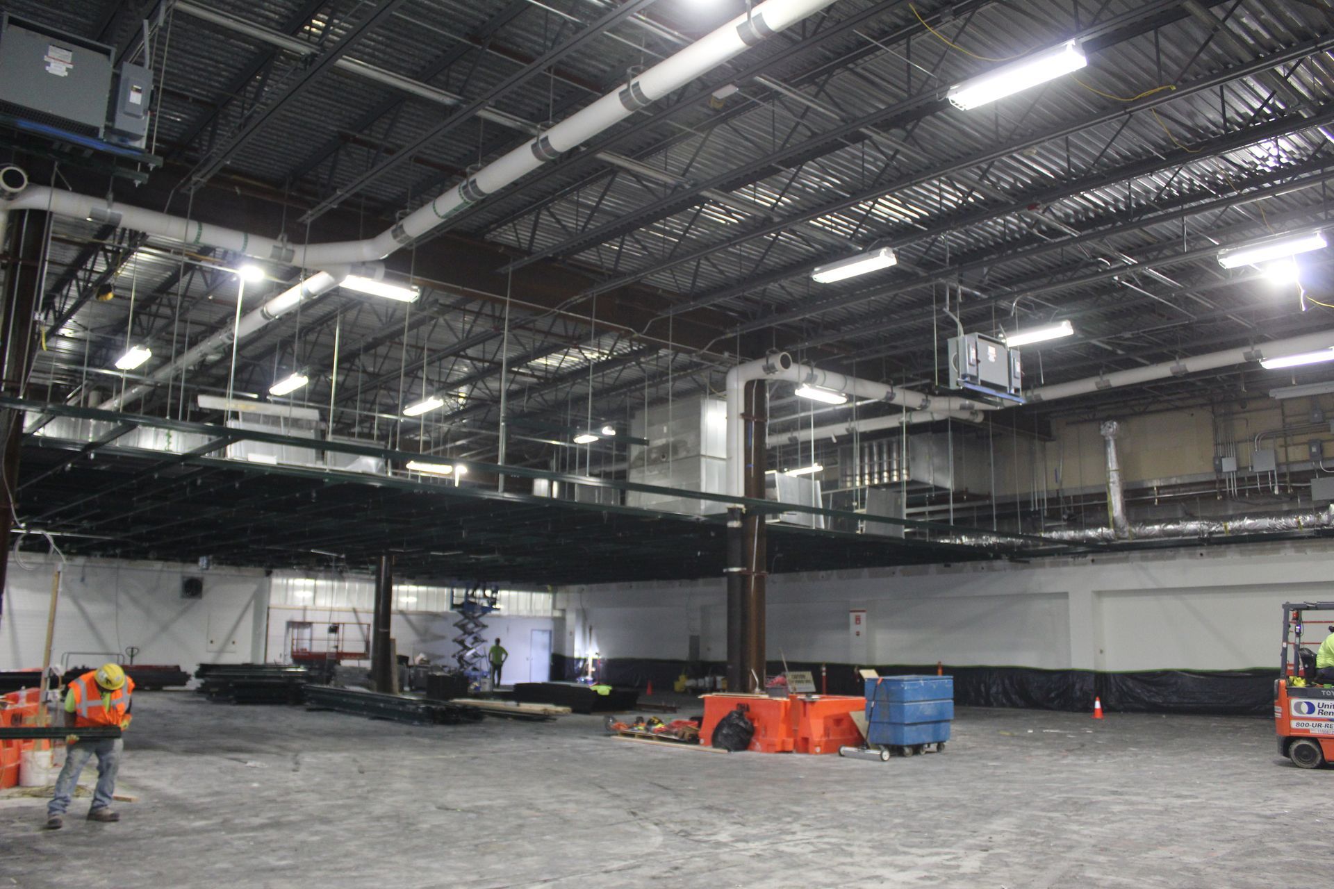 A man in a hard hat is standing in an empty warehouse.